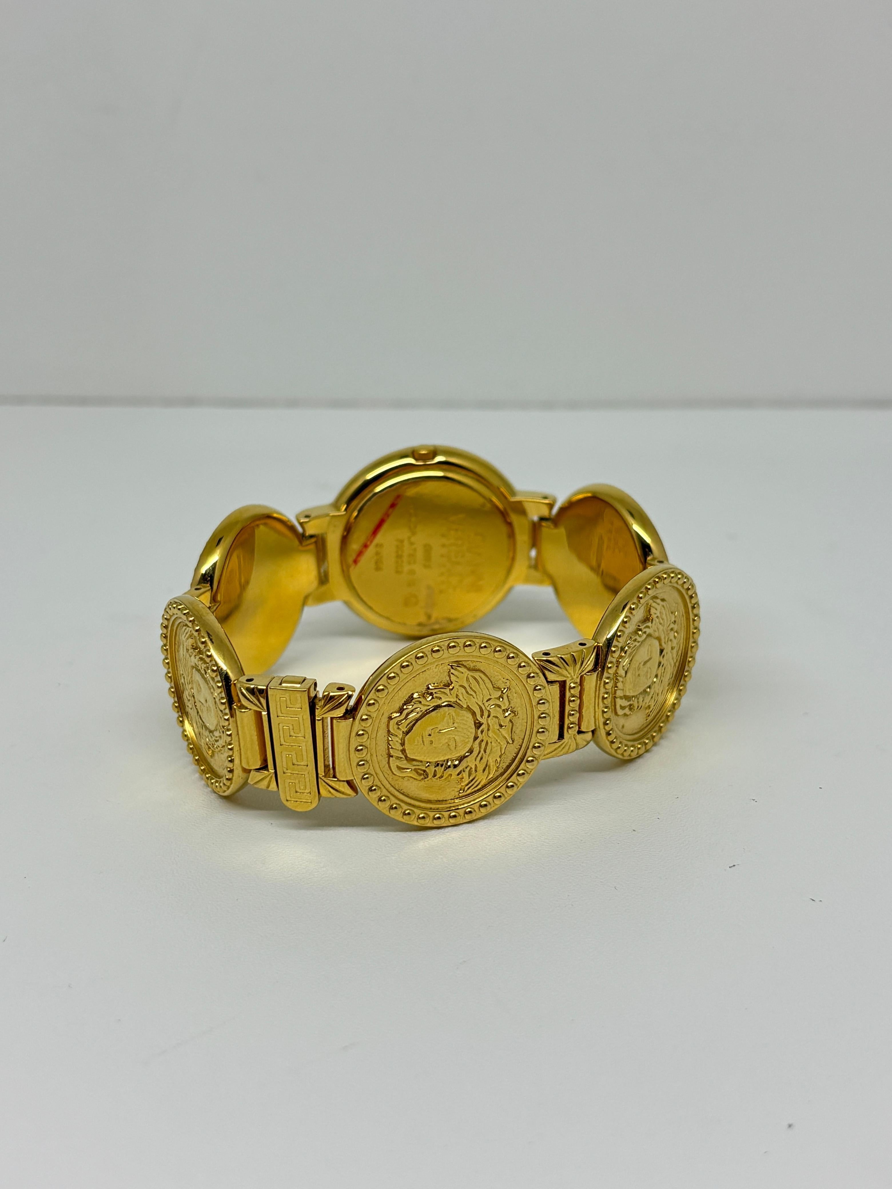 Vintage Gianni Versace gold medusa coin watch in all gold color. Légères éraflures mais très bon état vintage. La montre fonctionne encore. Le fermoir est un peu lâche mais peut être utilisé en toute sécurité. Longueur : 18 cm. S'ajuste légèrement à