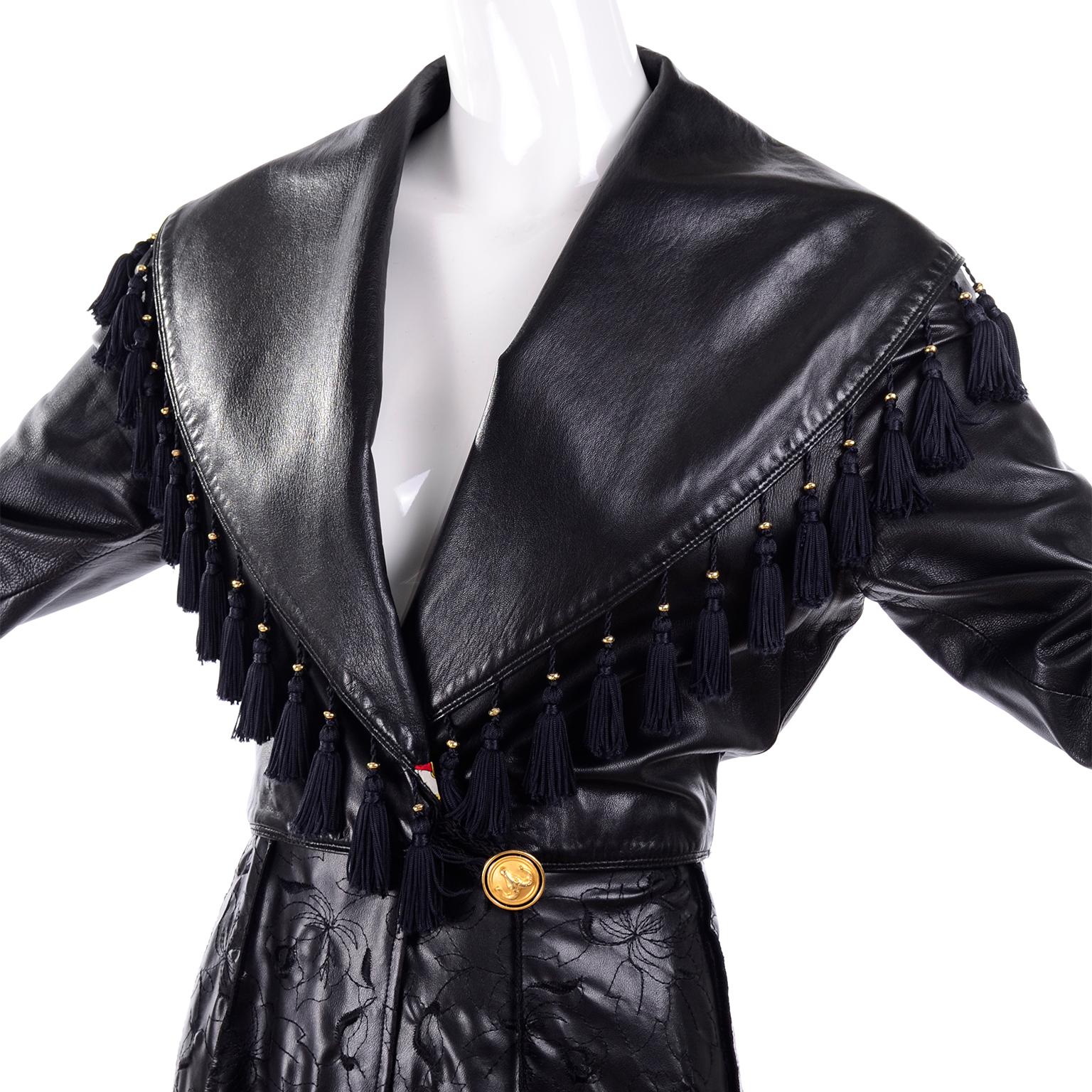 This is a very unique vintage Gianni Versace Coat in black leather with tassels. The coat closes with a ram's head button on the outside and gold medusa head button on inside. The bottom portion of the coat is embroidered leather with reverse seams