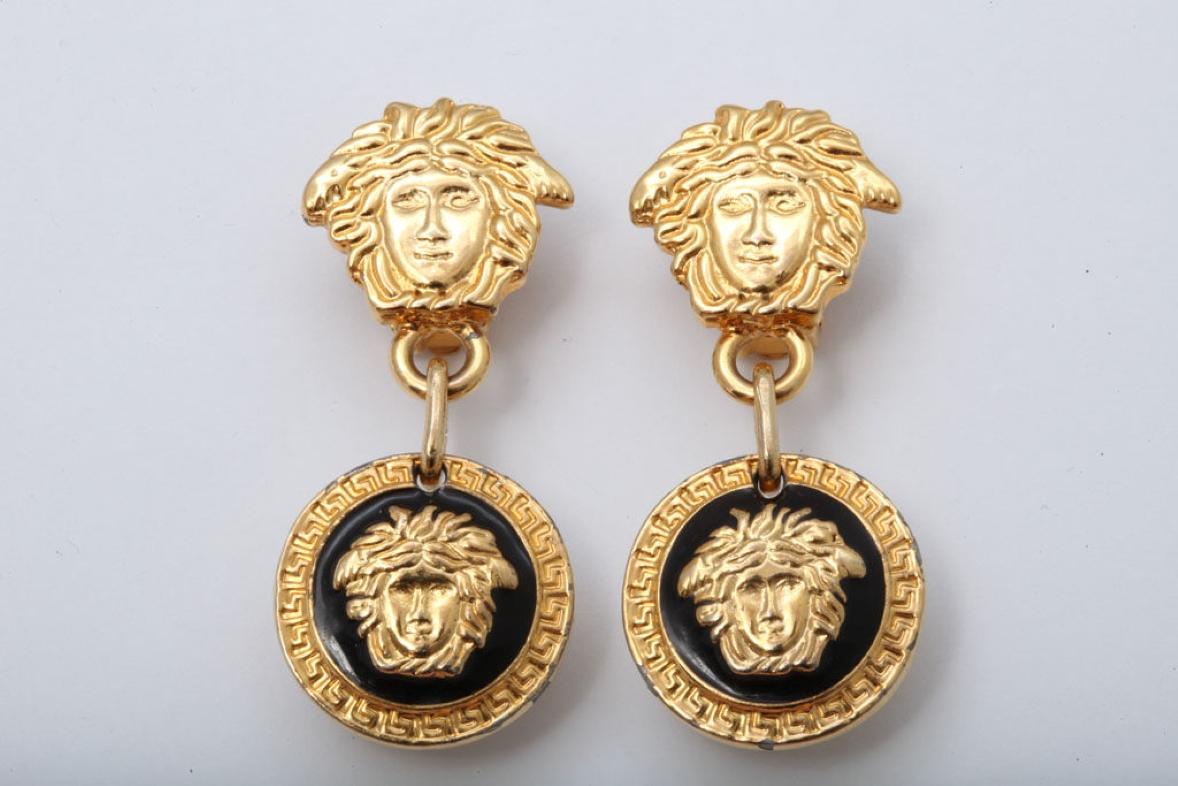 Boucles d'oreilles pendantes de la Méduse emblématique de Gianni Versace en or, noir et blanc. Clip-on.

Largeur : 1 pouce (25,4 mm)
Longueur : 2,16 in (54,87 mm)