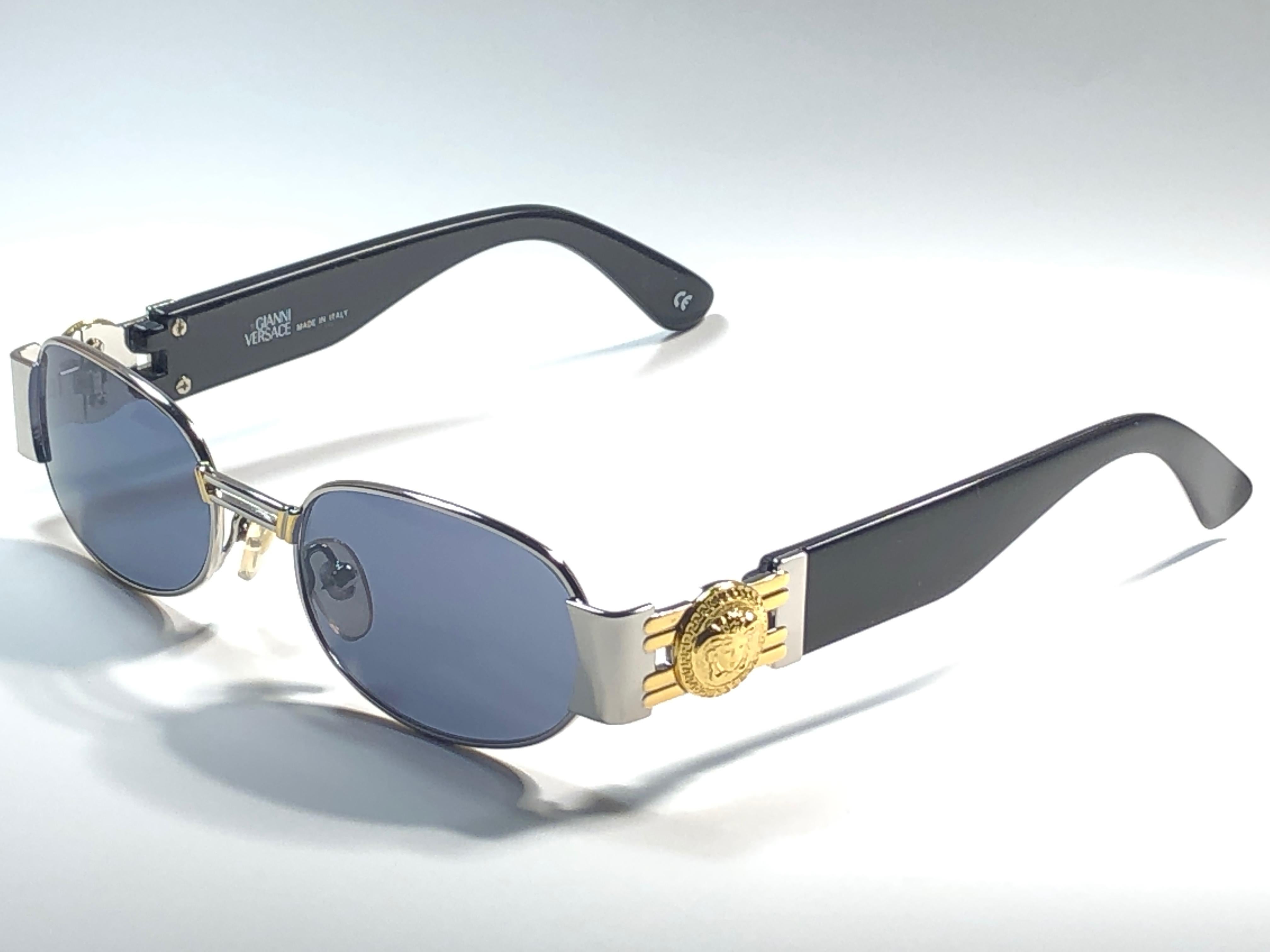 Vintage Gianni Versace petite monture noire & argentée avec des verres gris. 

Cette paire présente des signes mineurs d'usure dus au stockage. 

Fabriqué en Italie.