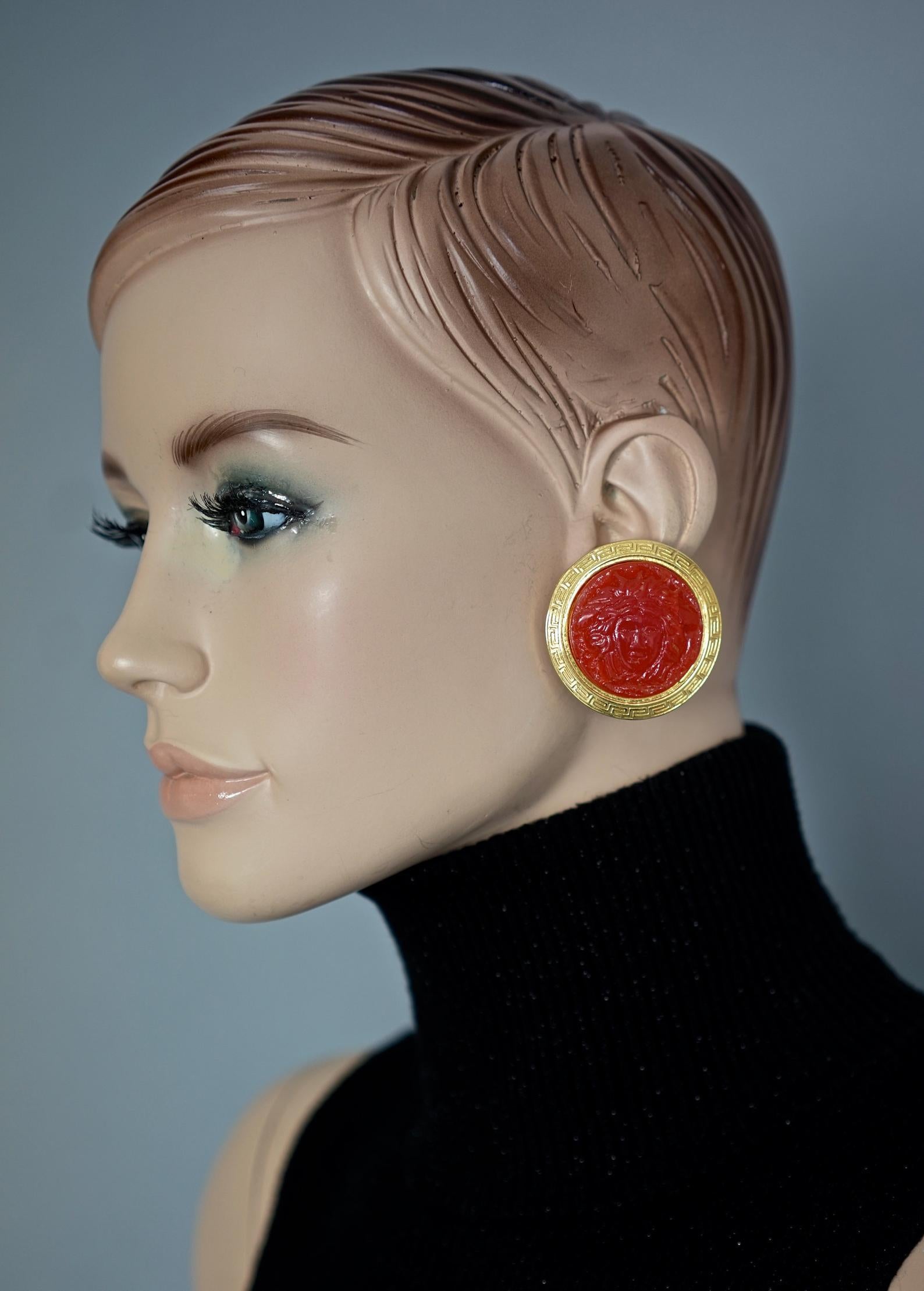 Vintage GIANNI VERSACE Red Medusa Greek Keys Medallion Disc Earrings

Measurements:
Height: 1.69 inches (4.3 cm)
Width: 1.69 inches (4.3 cm)
Weight per Earring: 23 grams

Features:
- 100% Authentic GIANNI VERSACE.
- Red Medusa head at the centre