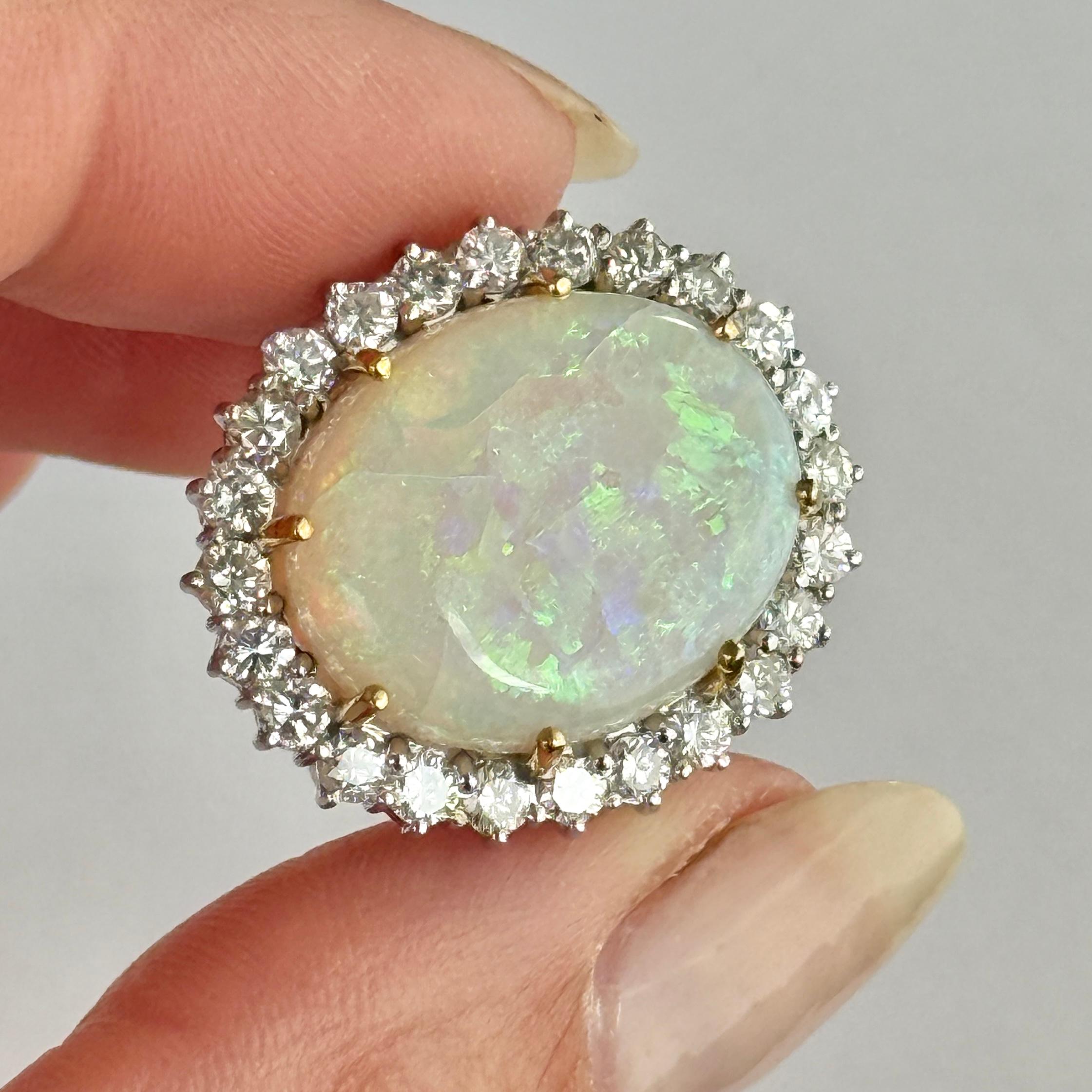 Au centre d'un étincelant halo de diamants se trouve une magnifique opale géante. Le halo de diamants contient 24 pierres d'une valeur totale d'environ 1,2 carats. Les bagues sont modelées en or 18 carats et les pierres sont serties en platine.