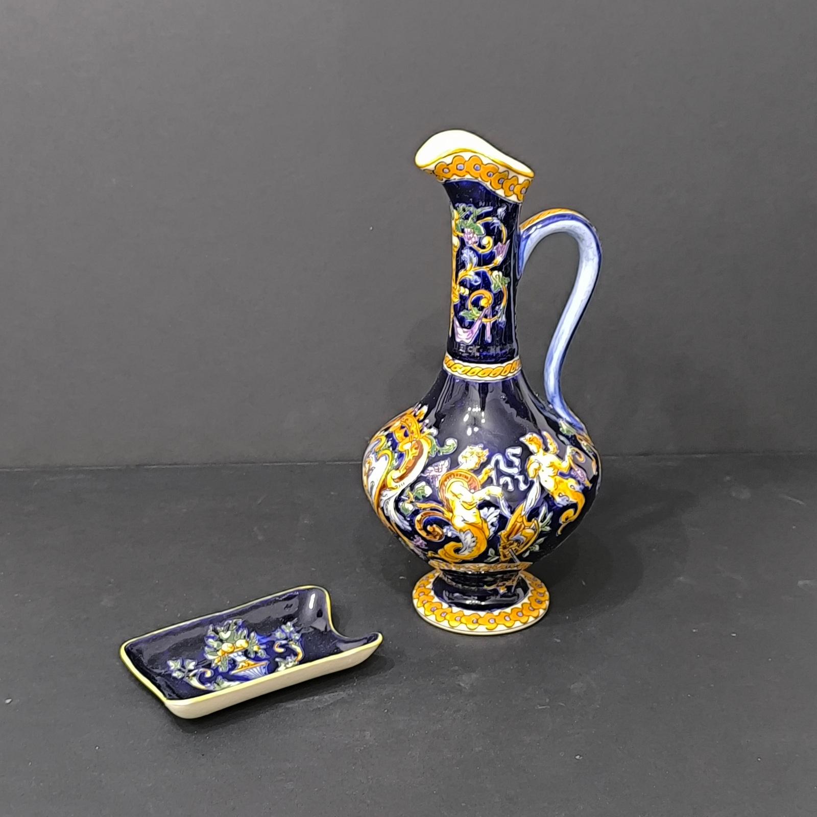 A beautiful set of ceramic pieces by Gien France, 1970s-1980s.
It comprises a jug and a small tray.
The jug is hand-painted with a Renaissance design against a royal blue glazed background, skillfully crafted with attention to detail. 
The small