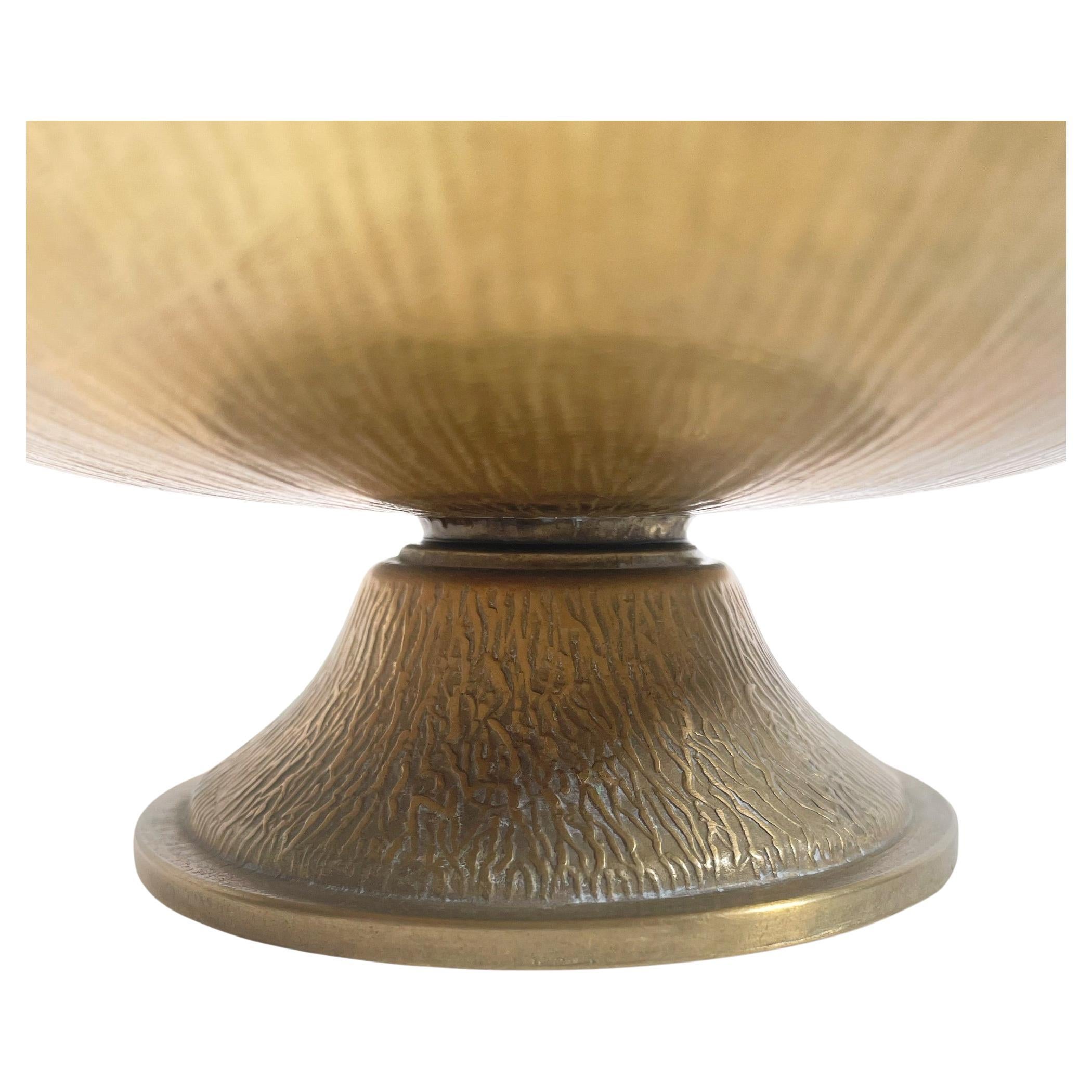 Ajoutez une touche de glamour rétro à votre espace avec cette exquise coupe vintage en bronze doré des années 1960. D'une hauteur de 8 cm et d'un diamètre de 19 cm, cette pièce élégante présente une finition dorée rayonnante qui exsude la