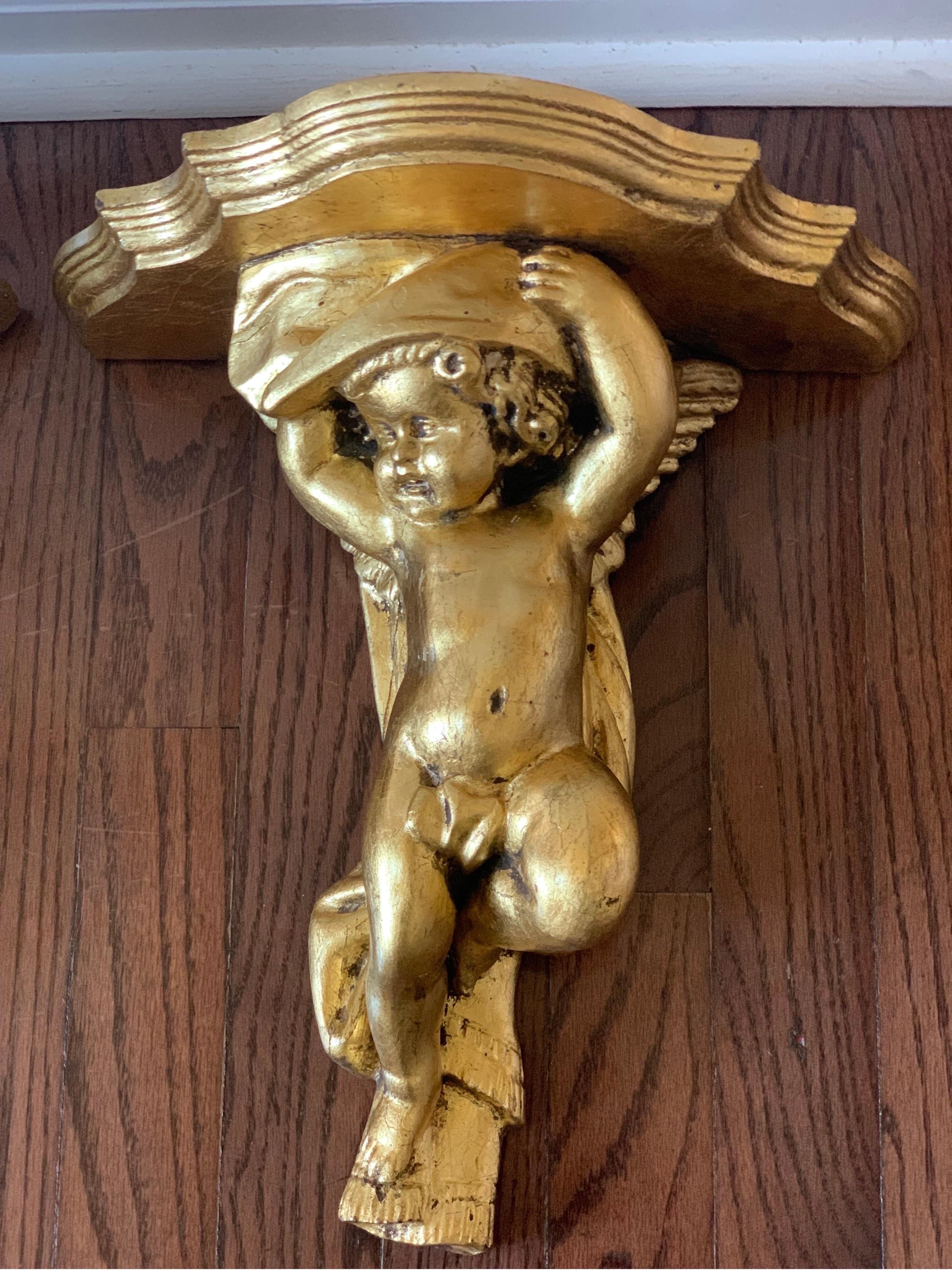 Charming pair of European hand carved gilt cherub wall bracket shelves, c. 1920. Hand crafted depicting an authentic pair with beautiful detail. Hooks are intact. In good condition.