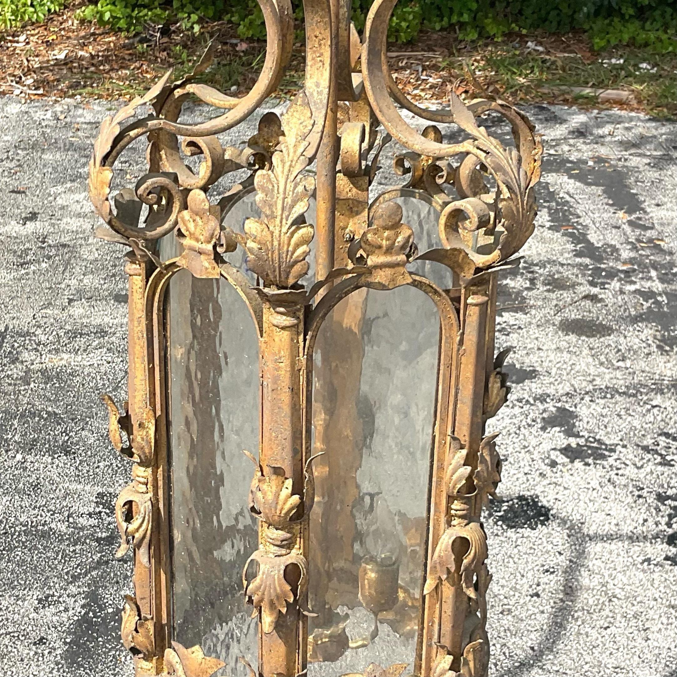 Amazing gilt French style hanging lantern with leaf appliqué. The lantern has rippled glass in each of the intricate 6 arched openings. Fantastic touch of glamour for any space. Acquired from a Palm Beach estate.