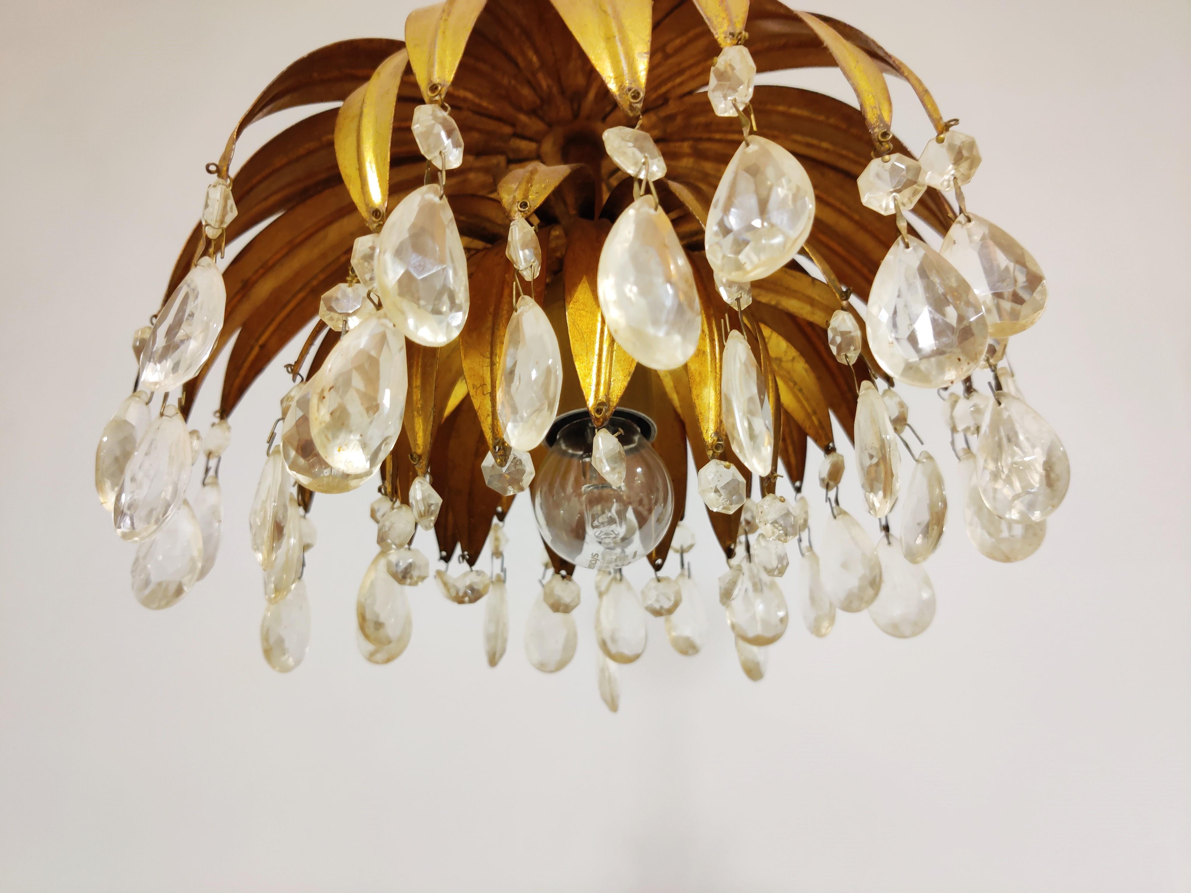 Midcentury gilt metal palm leaf pendant light

This gilt metal leaf chandelier was made in italy and has crsytal droplets

1960s - Italy

Tested and ready to use with regular E27 light bulb.

Dimensions:
Height 38cm/14.96
