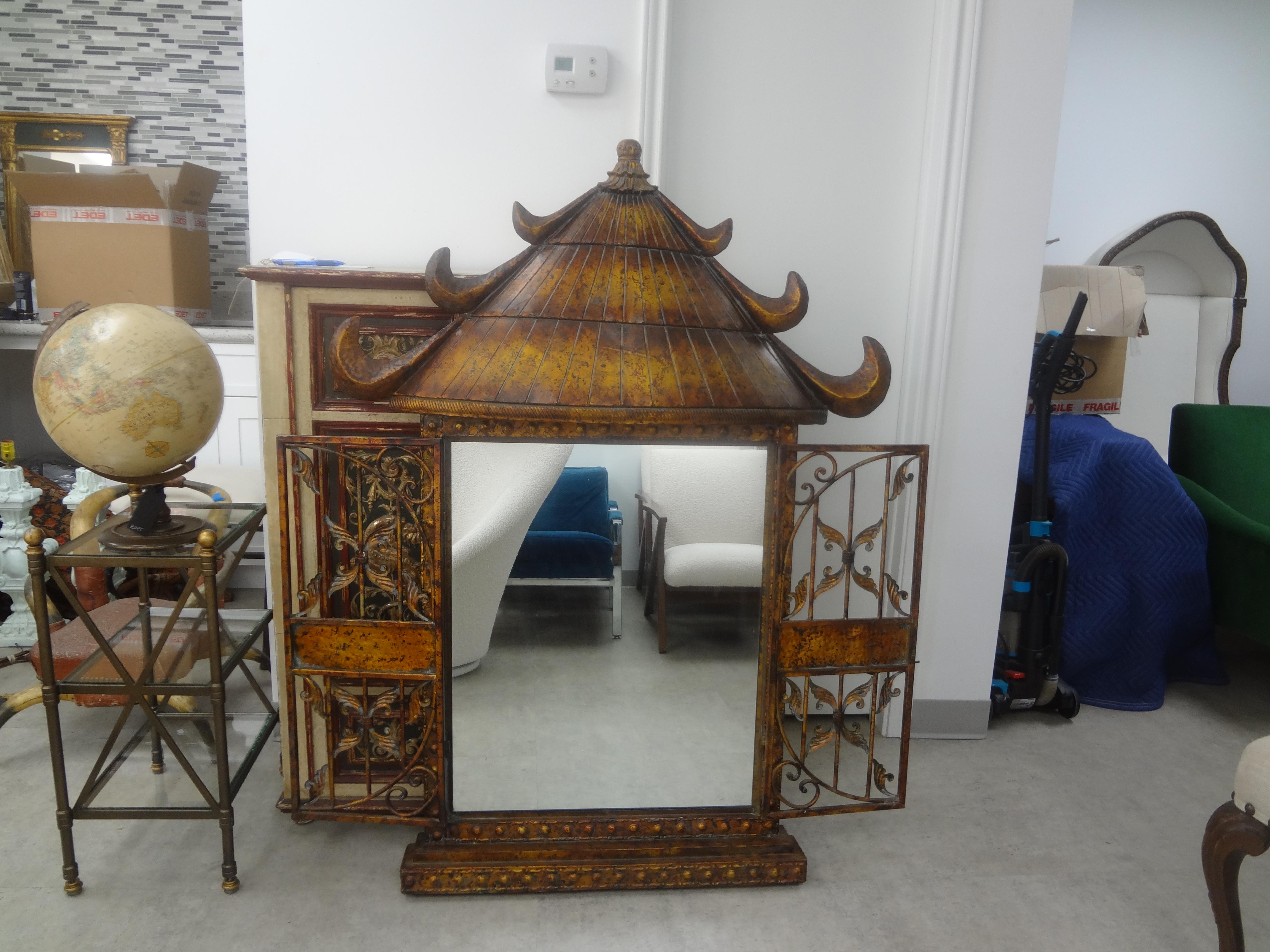 Vintage gilt metal pagoda mirror.
This stunning Hollywood Regency style gilt metal mirror in the shape of a pagoda has two doors that can either stay open or latch closed. Each door has beautifully detailing and lions head motif.
