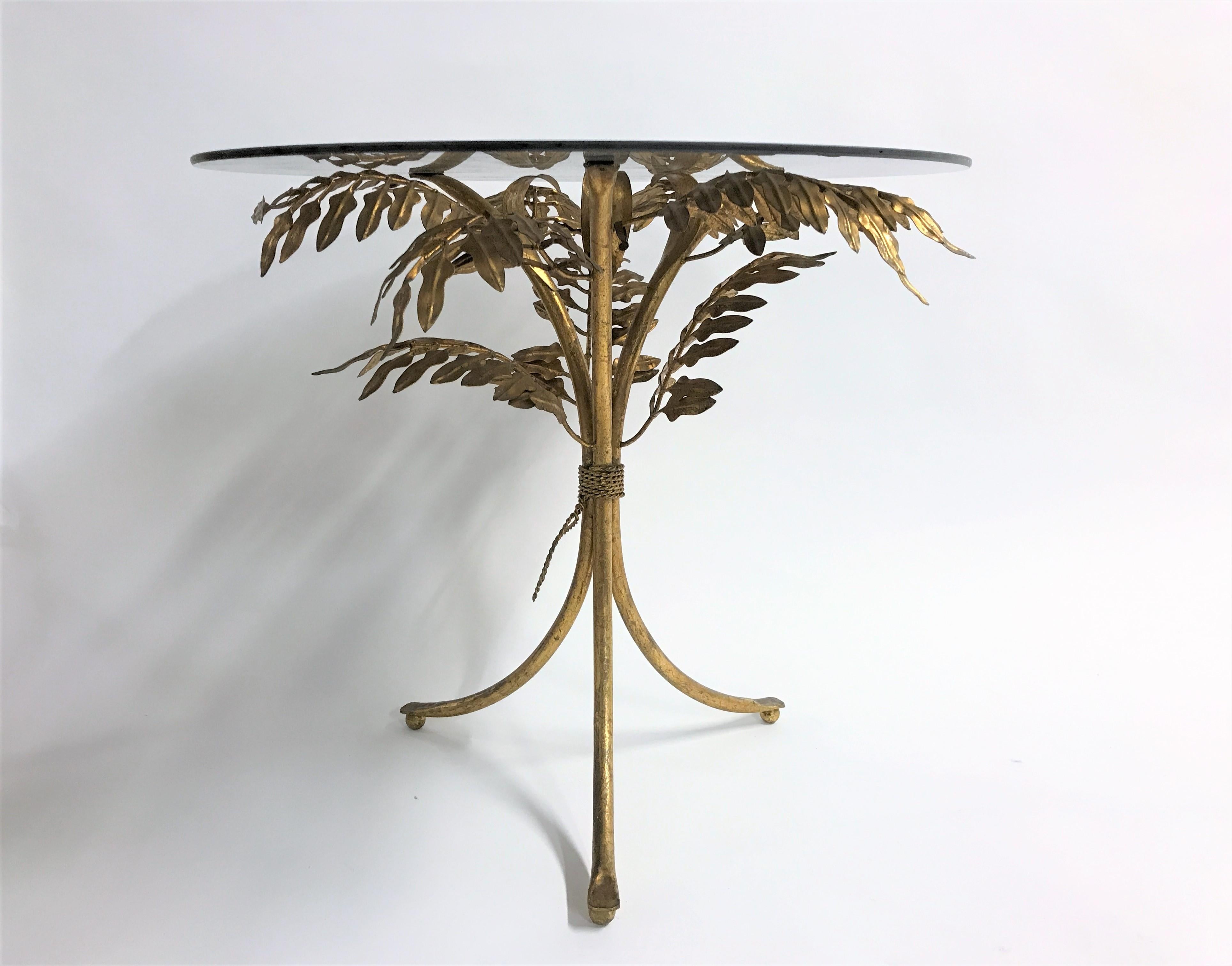 Charming gilt metal palm tree side table with a round smoked glass top.

The table was manufactured in Italy, it is labeled with 'made in italy'.

Beautiful patina.

Good condition, glass has no damage.

1960s, Italy

Neasures: Height