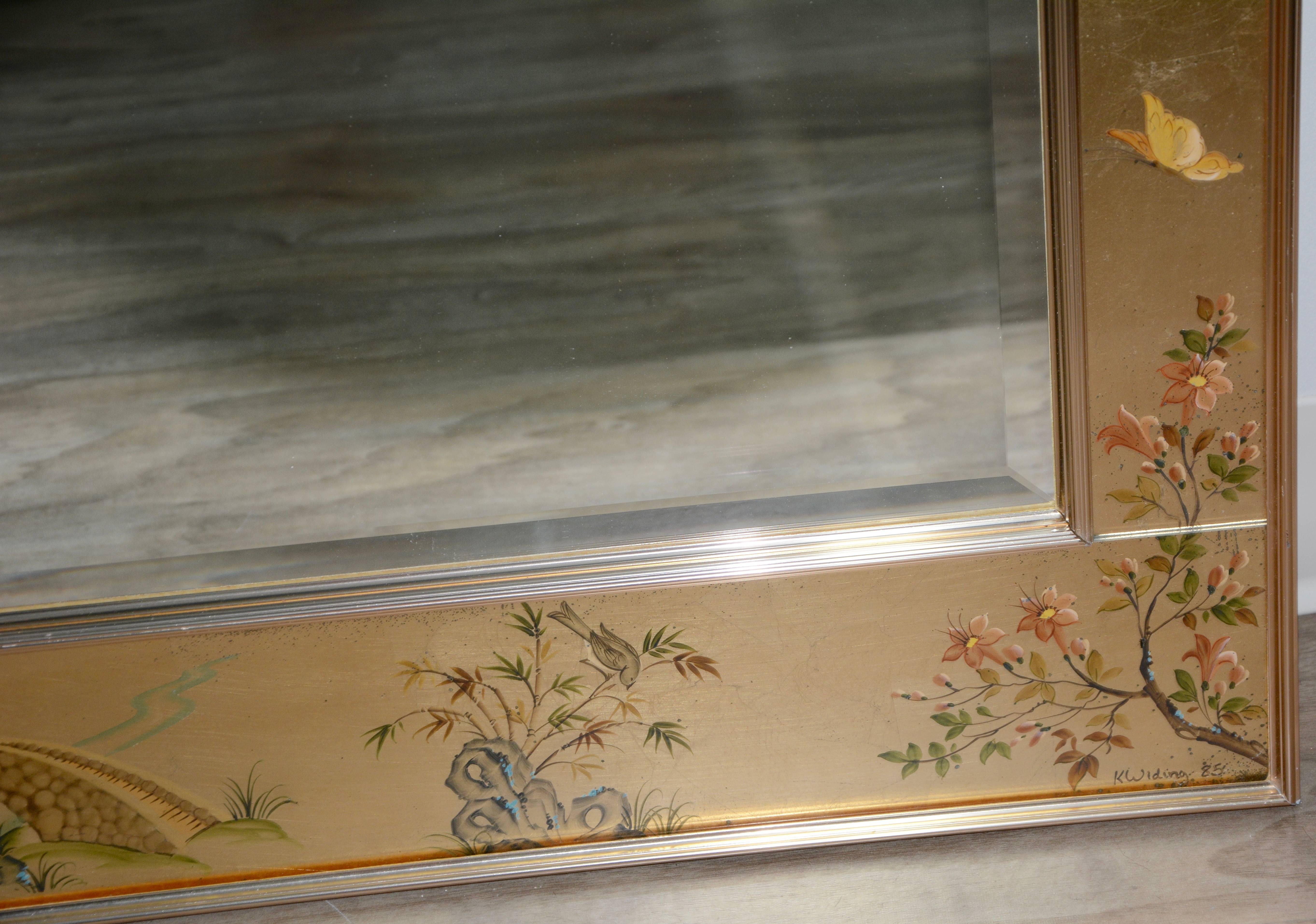 Nous vous proposons un miroir mural vintage de style chinoiserie peint et doré par Labarge. Ce miroir présente un grand miroir en verre biseauté encadré par des panneaux de verre peints en or avec des motifs naturels, figuratifs et architecturaux