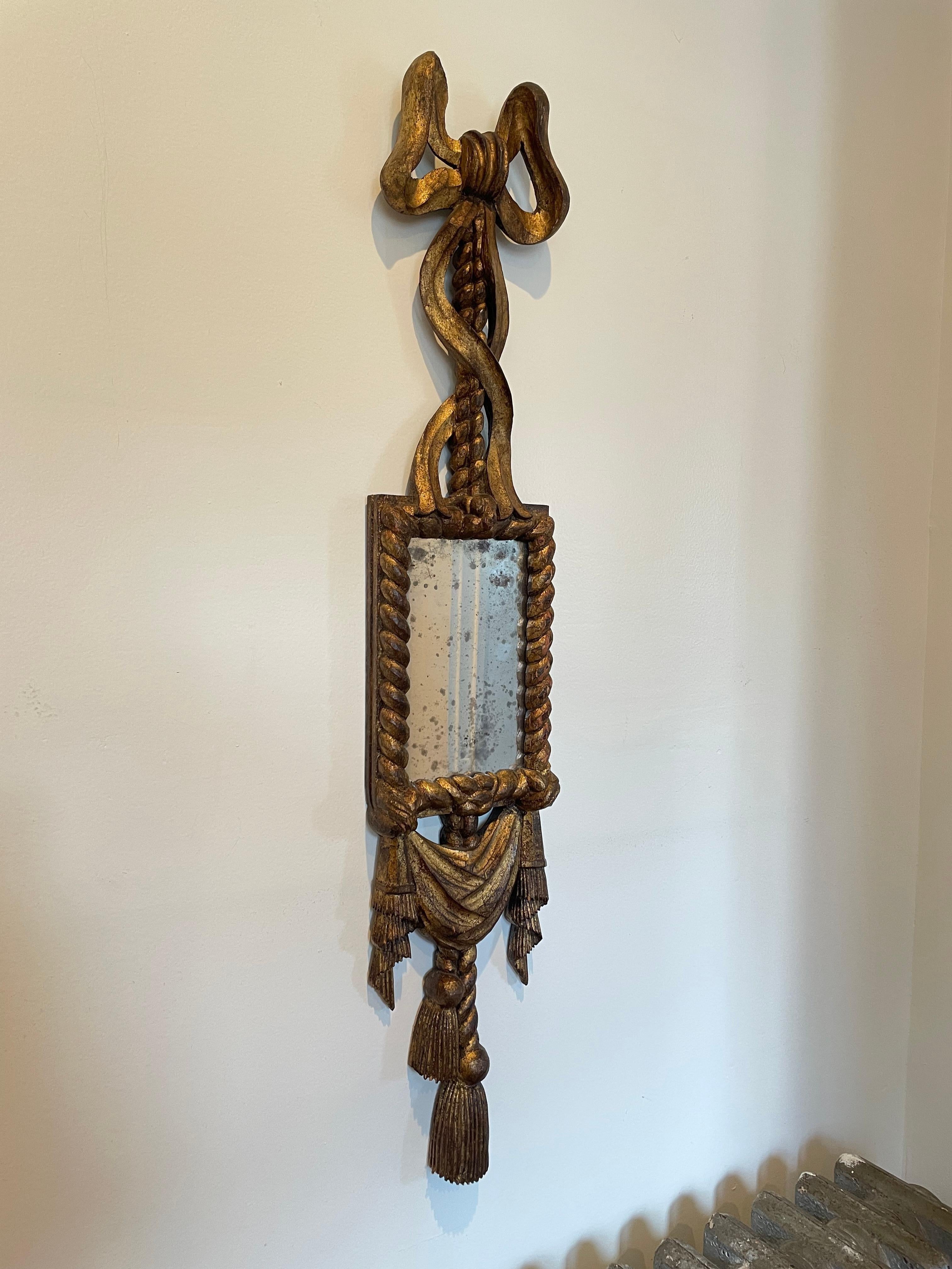 Beautiful detail in this giltwood mirror with ribbon, rope and drape detail. Nicely antiqued mirror surface. Marked Spain.