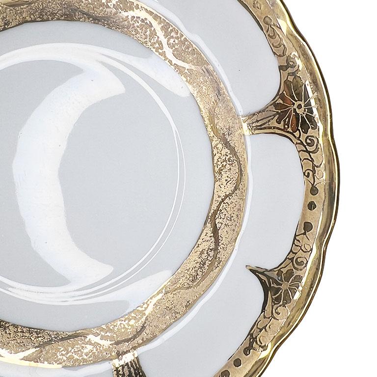Un magnifique plat décoratif doré avec des détails en or. Réalisé dans une porcelaine délicate d'un blanc éclatant, ce joli plat présente des bords ondulés dans un motif de festons. Les bords sont ornés d'un motif floral stylisé en relief. Ce plat