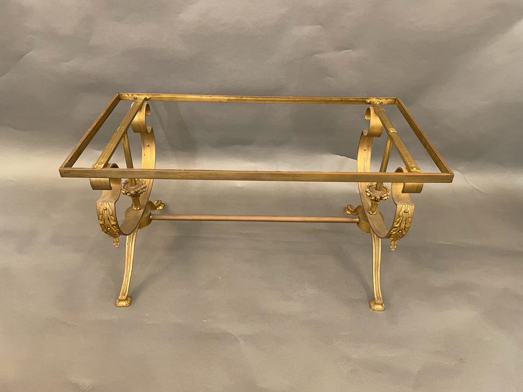 The glamorous rectangular Gilbert Poillerat style, circa 1940s vintage coffee/cocktail table has Rococo gilt wrought bronze legs adorned with beautiful decorations attached to a stretcher. The top is a mirror set into a gilt wrought bronze frame and