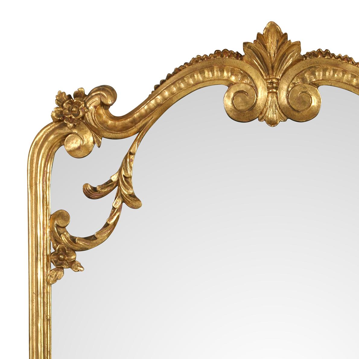 A rectangular giltwood mirror with a curved top.  Although substantial in size, the mirror has a light, airy feel.  The sides are molded and the top and base feature lovely carving in the Rococo style.  This lovely mirror would work in a bedroom,
