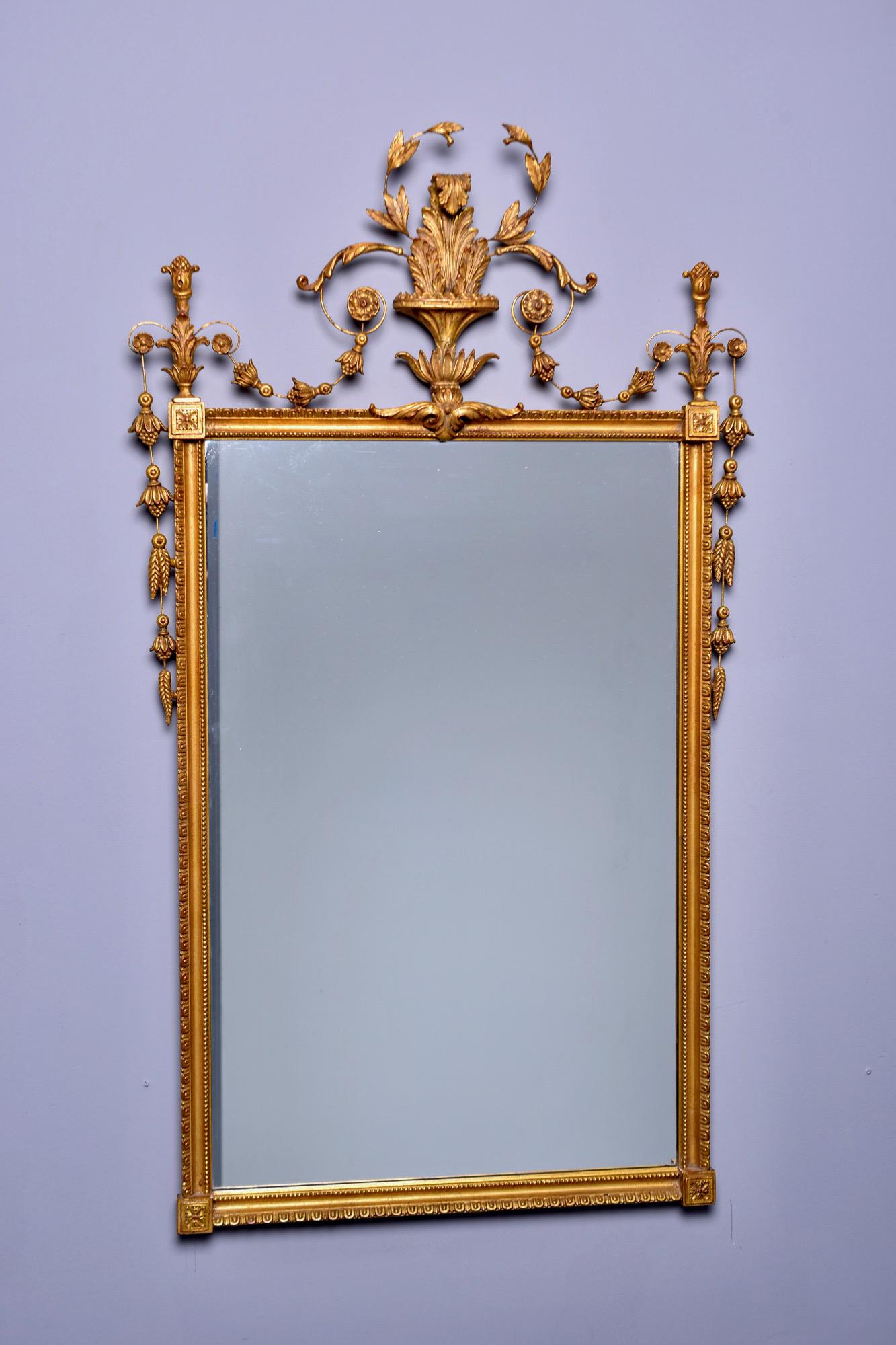 Fancy giltwood mirror with rectangular frame and fancy crest with floral and foliate detail. Labeled on back D. Milch and Sons, circa 1950s. 

Actual mirror size: 33.25” H x 21.25” W.