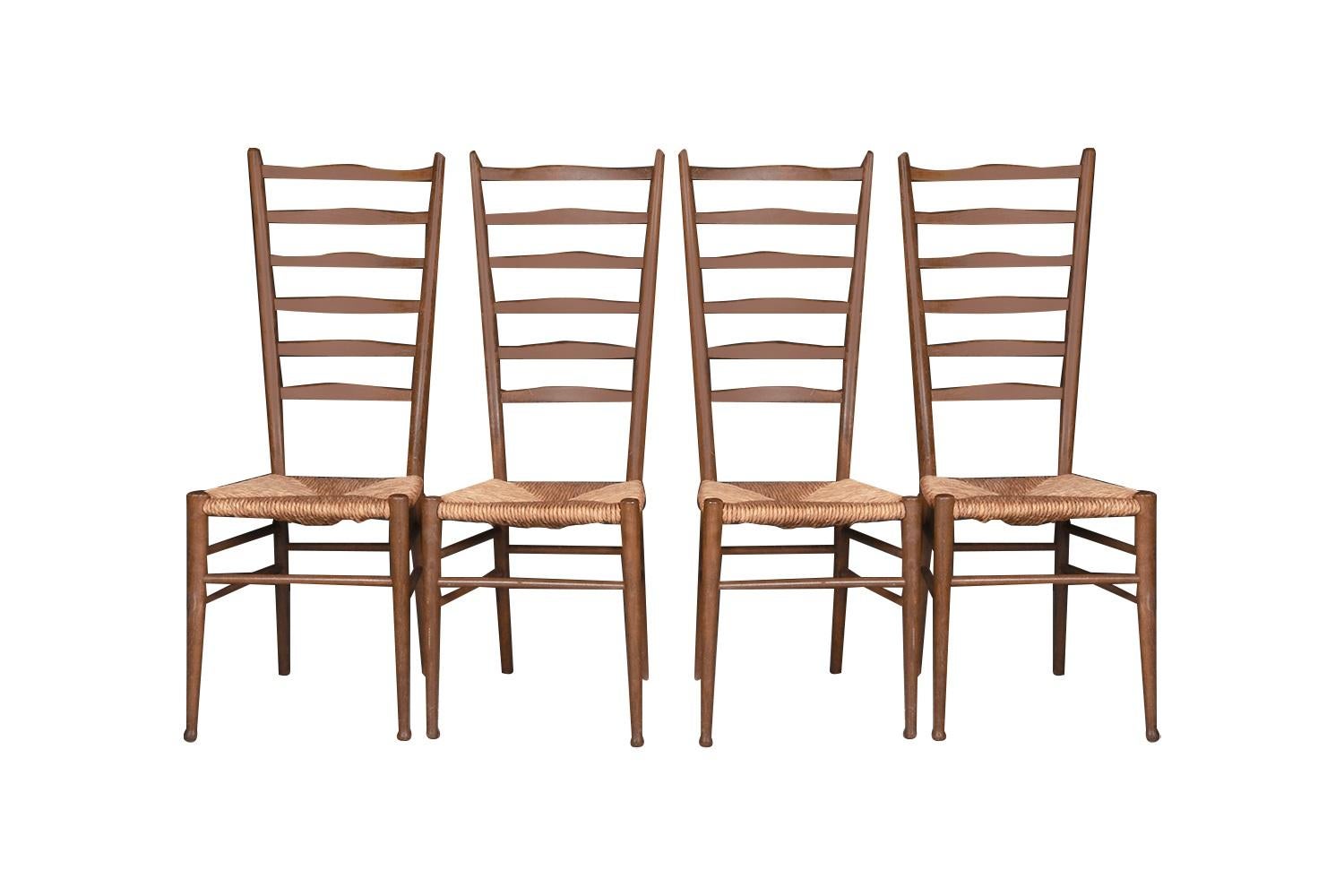 Exceptional set of four tall ladder back dining side chairs in the style of Gio Ponti, Italy, c. 1950s. Each chair features a high back, with six horizontal slats, woven natural paper cord rush seats, and a handsome leg design with splayed back legs