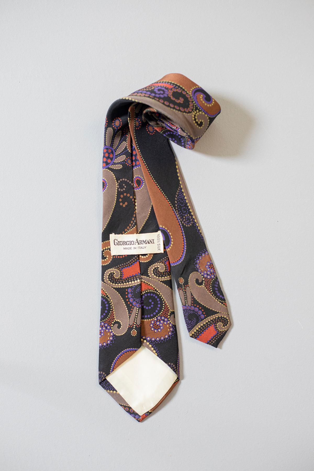 This vintage tie designed by Giorgio Armani is elegant and unique. Its pattern recalls paisley and its vivid colours on a black background make it just enough showy. This tie is in all silk and it is perfect for a party or for a night out with your