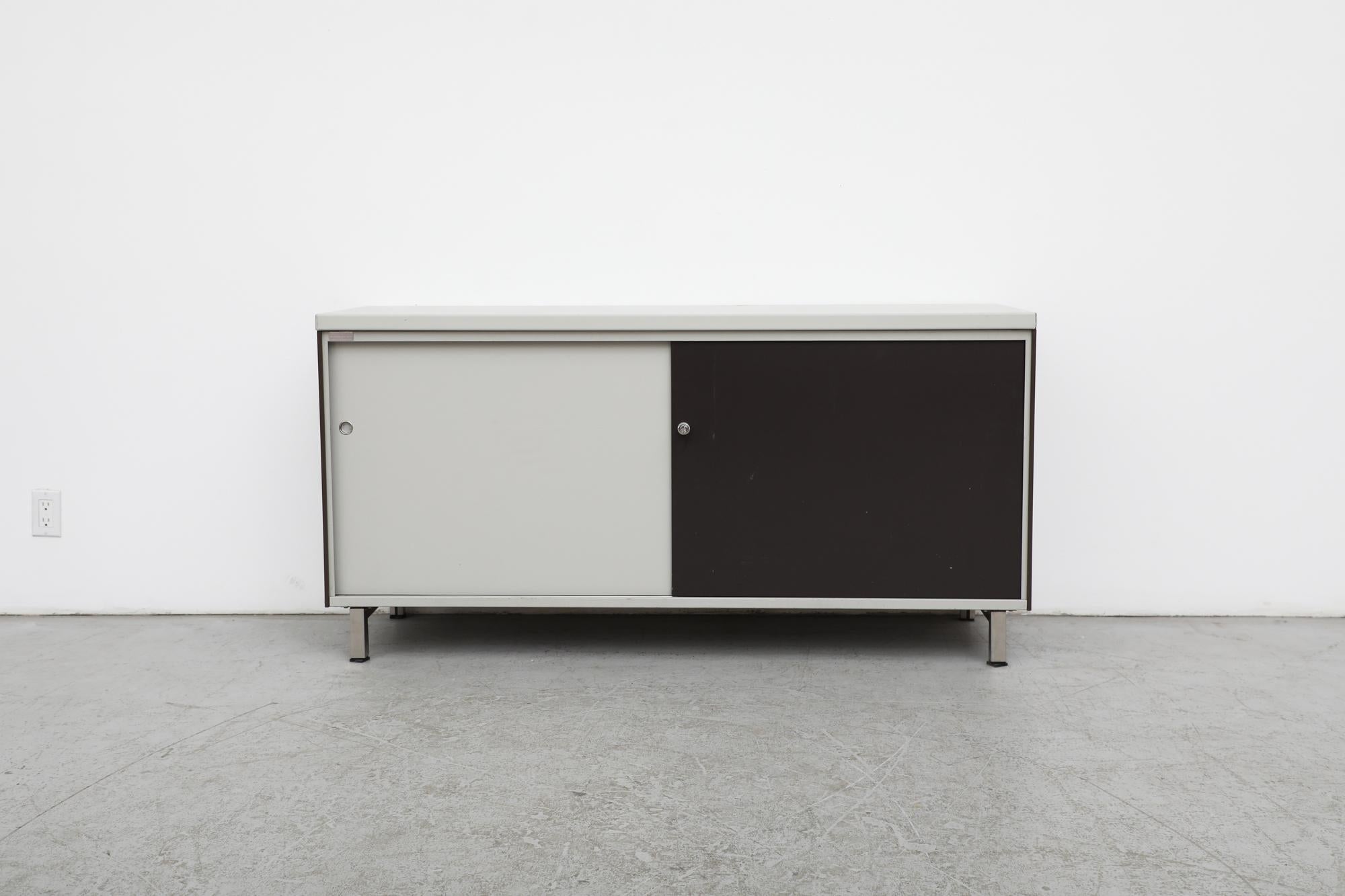Gispen armoire industrielle en métal émaillé gris clair et noir à deux tons avec dessus gris, portes coulissantes et pieds chromés. Parfait comme armoire de bureau ou crédence. Les dos sont finis et peuvent être utilisés comme séparateur de pièce ou
