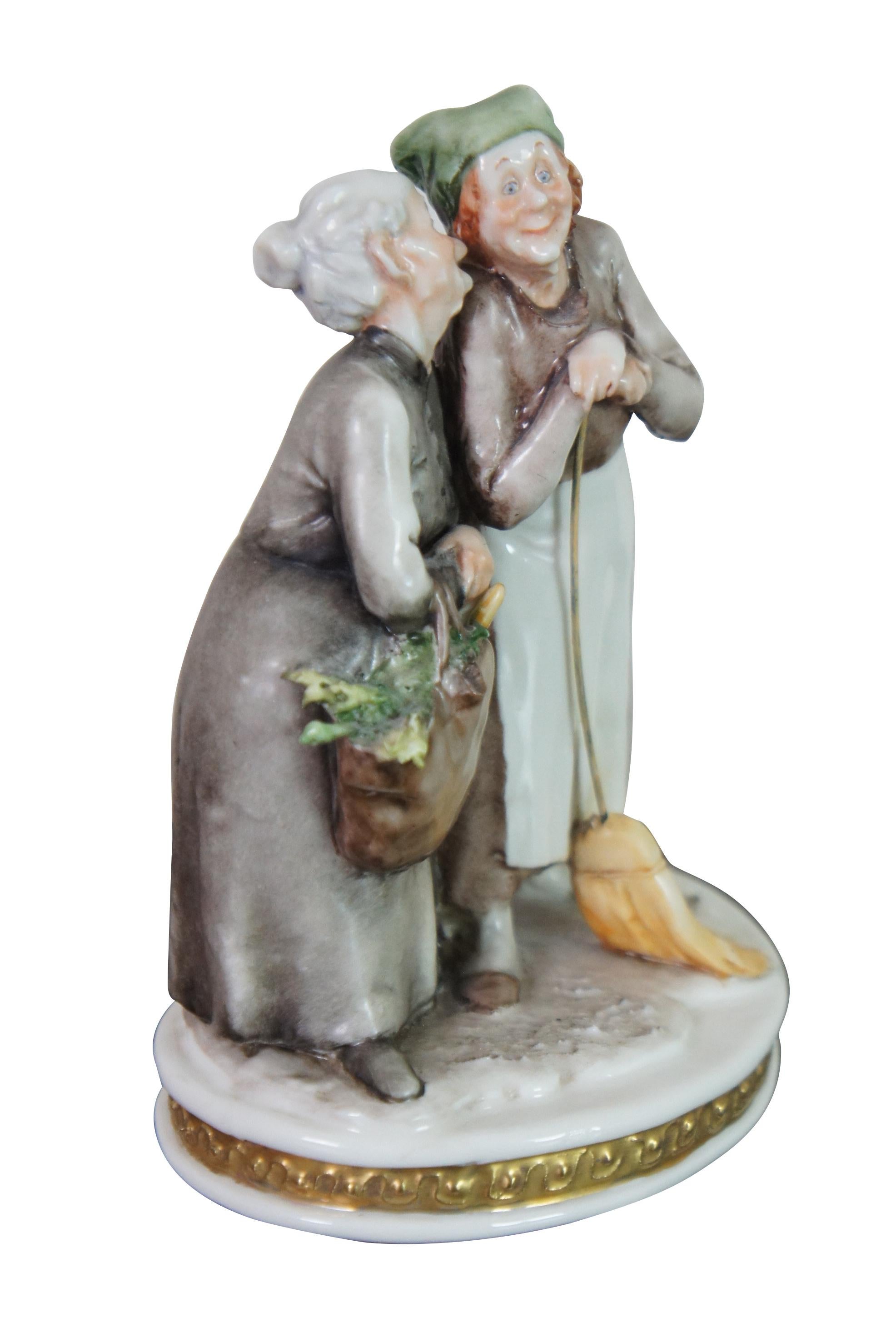 Rare original Italian Giuseppe Cappe Capodimonte porcelain figurine featuring two elderly women, one with a broom, and the other with groceries, whispering / gossiping to each other, next to a small white cat. Made in Italy, 5 prong crown N mark.
 