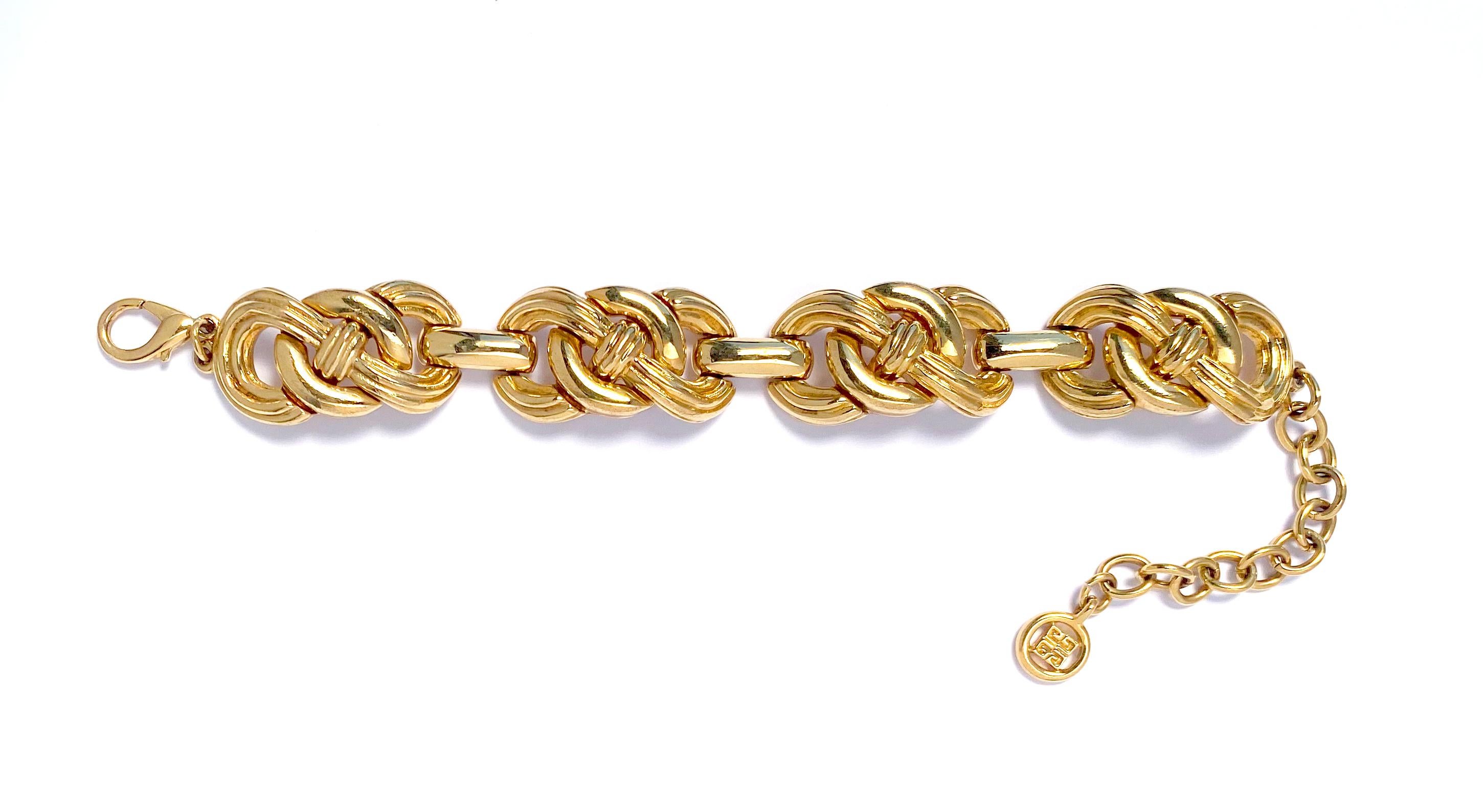 1980er Vintage Givenchy Kettenarmband mit großen verschnörkelten Gliedern aus Goldblech.  Dieses Vintage-Armband besteht aus polierten Gliedern in offener Knotenform mit Karabinerverschluss und Verlängerungskette mit Givenchy-Logo.   Armband misst