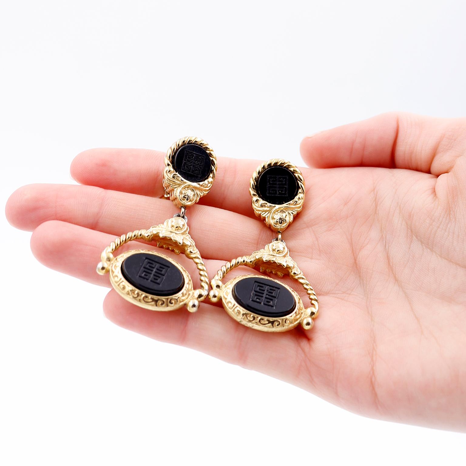 These vintage Givenchy door knocker style earrings feature twisted gold plated metal and a round and oval black matte enamel that has the givenchy logo engraved in the center. These great vintage drop earrings are so elegant and they have clip