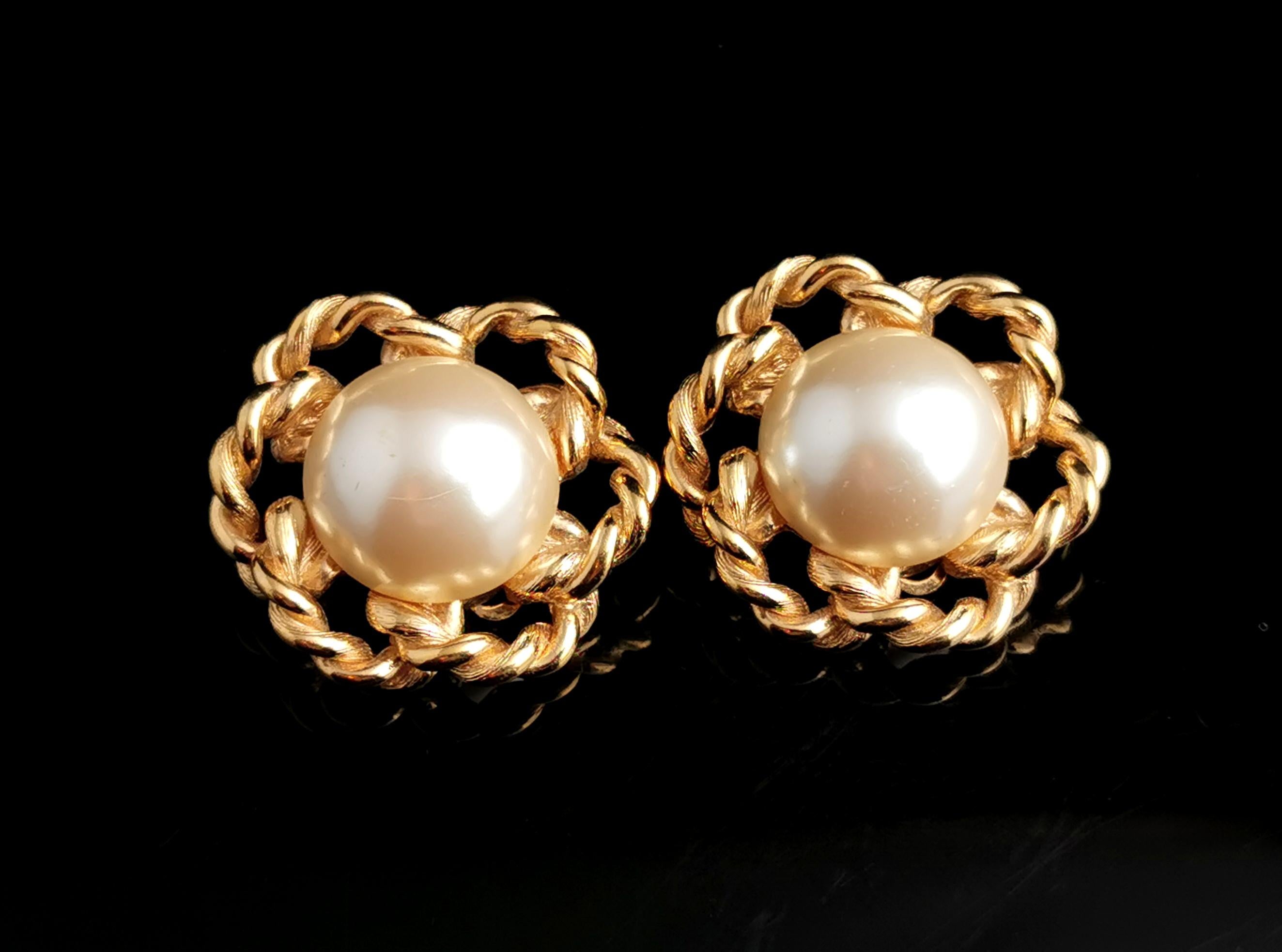 A fantastic pair of vintage Givenchy faux pearl clip on earrings.

A large pair of earrings in gold tone, lightly textured metal with an open work rope twist design.

Each earring is set with a large creamy lustrous faux pearl cabochon.

The