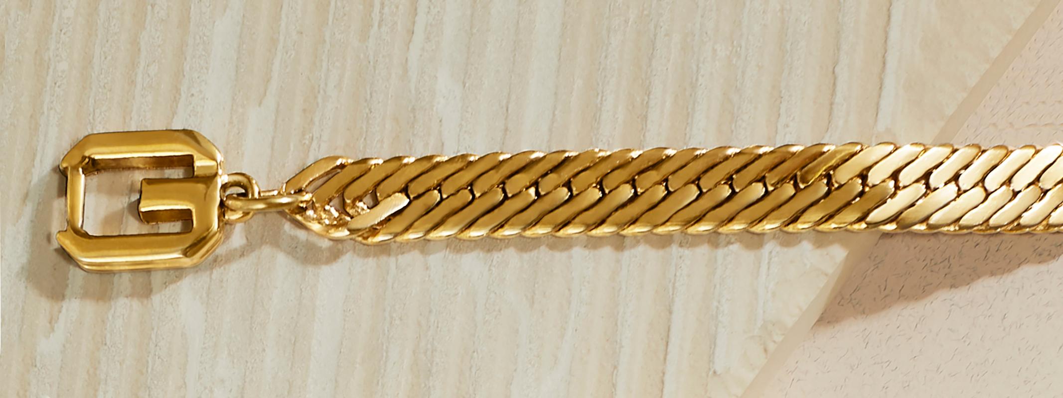 1980s Vintage Givenchy herringbone chain bracelet in gold plate.  This vintage bracelet features a flat, wide herringbone chain with a statement double G logo clasp.   Bracelet measures 7 1/4 inches in length, width just over 1/4 inch with a