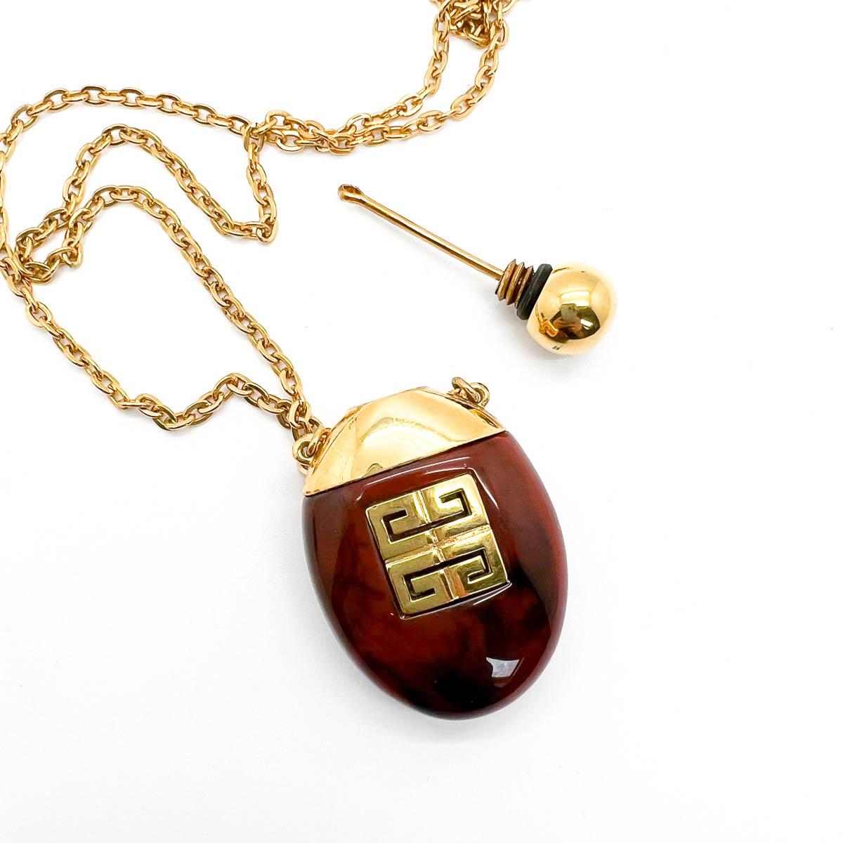 Our Vintage Givenchy Perfume Necklace dating to 1977 is one of the most iconic pieces from the House. A faux tortoiseshell bottle decorated with a gold screw cap and shoulders is finished to perfection with a large 4G logo from the House. This