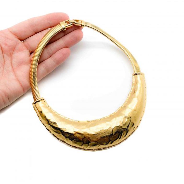 Un étonnant collier Torque Vintage Givenchy moderniste des années 1980. Il présente un impressionnant panneau de style torque en or brossé martelé, suspendu à une chaîne serpent articulée en or brillant, et terminé par l'emblématique fermeture G. En