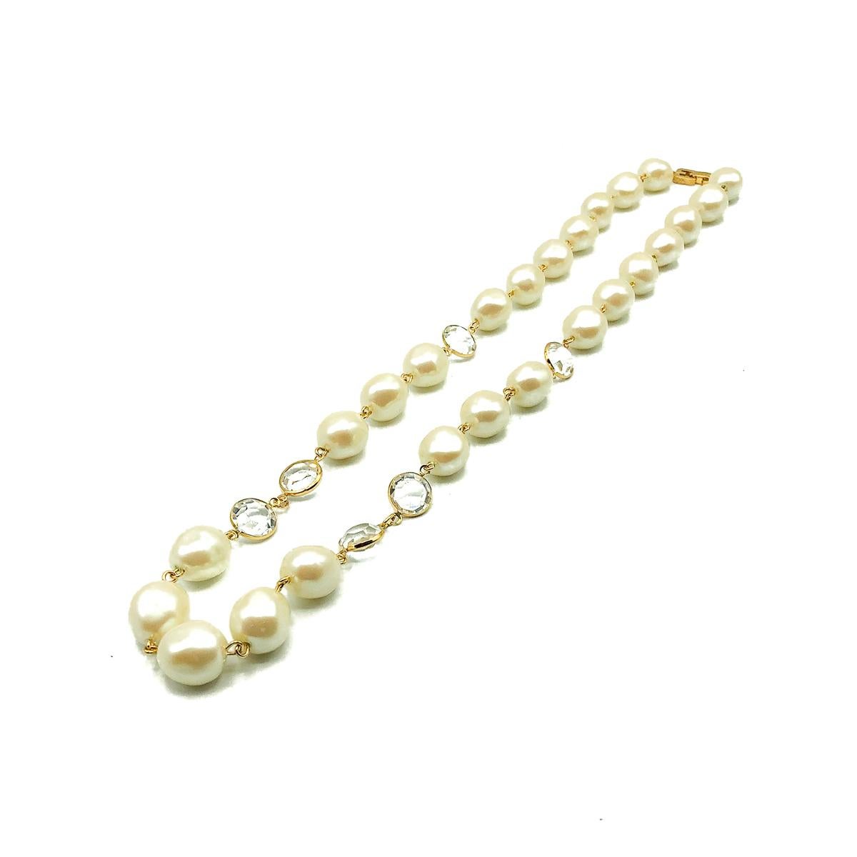 A Vintage Givenchy Pearl Necklace. Featuring a matinee length rope of glass faux pearls interspersed with mounted Swarovski crystals and finished with a double G logo clasp. Gold plated metal. 61cms. In very good vintage condition. Signed. With