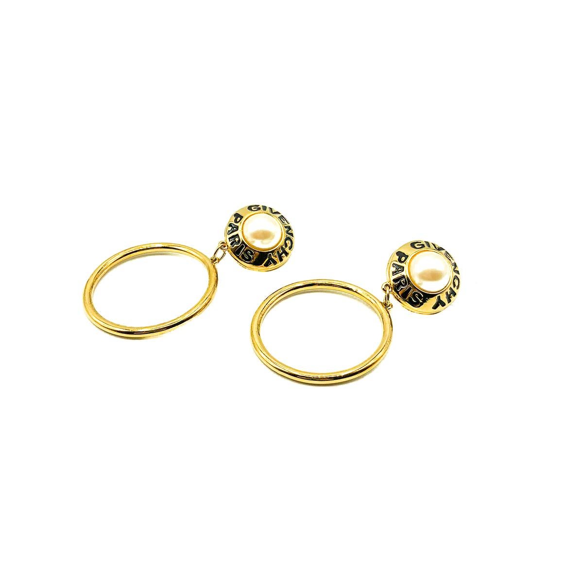 A pair of the most spectacular Vintage Givenchy Logo Hoop Earrings. Crafted in gold plated metal, black enamel and glass pearls. Featuring a lustrous pearl top surrounded by the iconic Givenchy name in black and a large gold front-facing hoop drop.