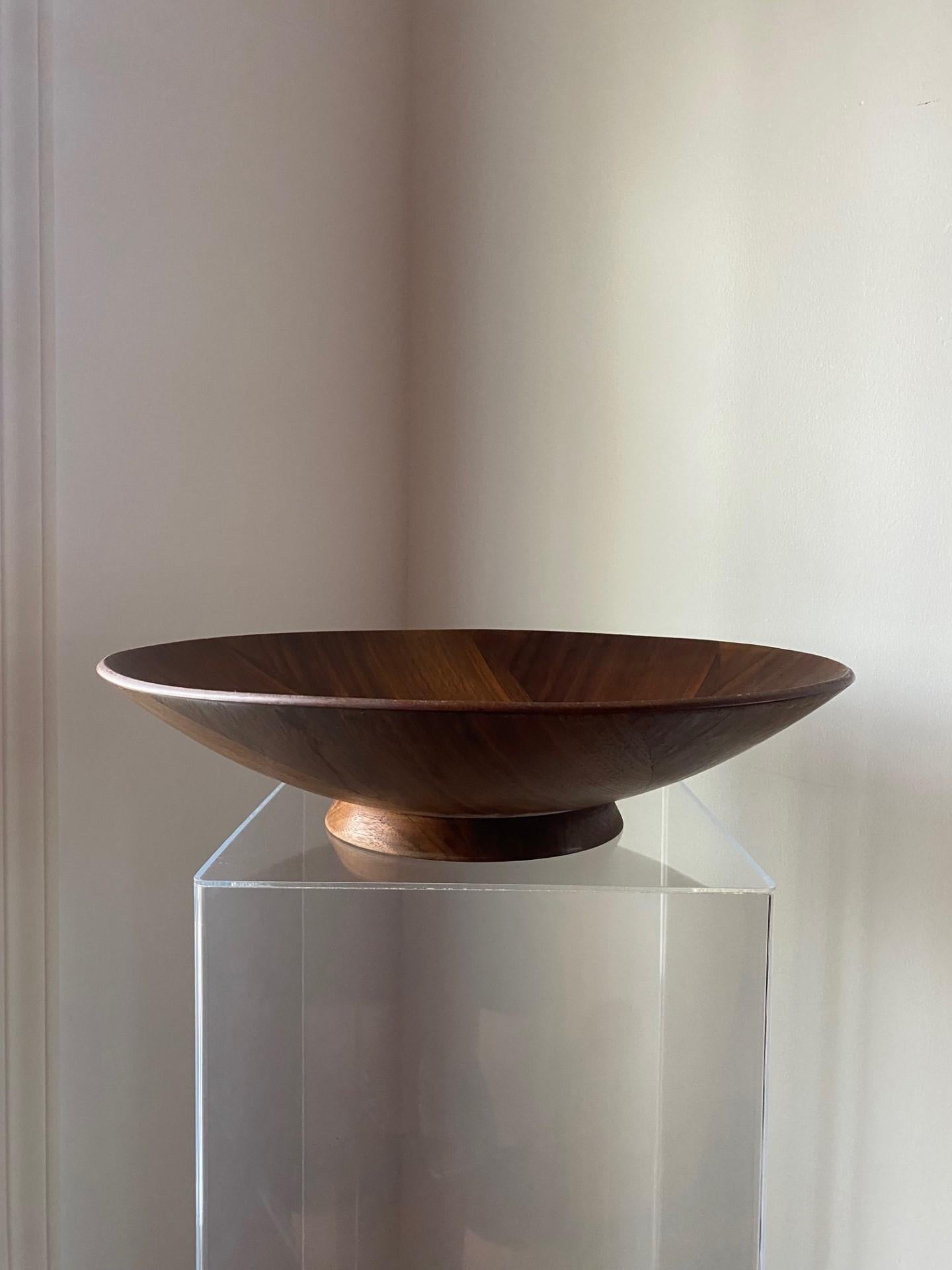 Beautiful serving bowl. Made in the USA and dating to the 1960s, this piece in an iris/aperture design with veneered inlays of teak on a walnut footed base is incredible. Organic and sculptural, the design is welcomed in any type of décor. There is