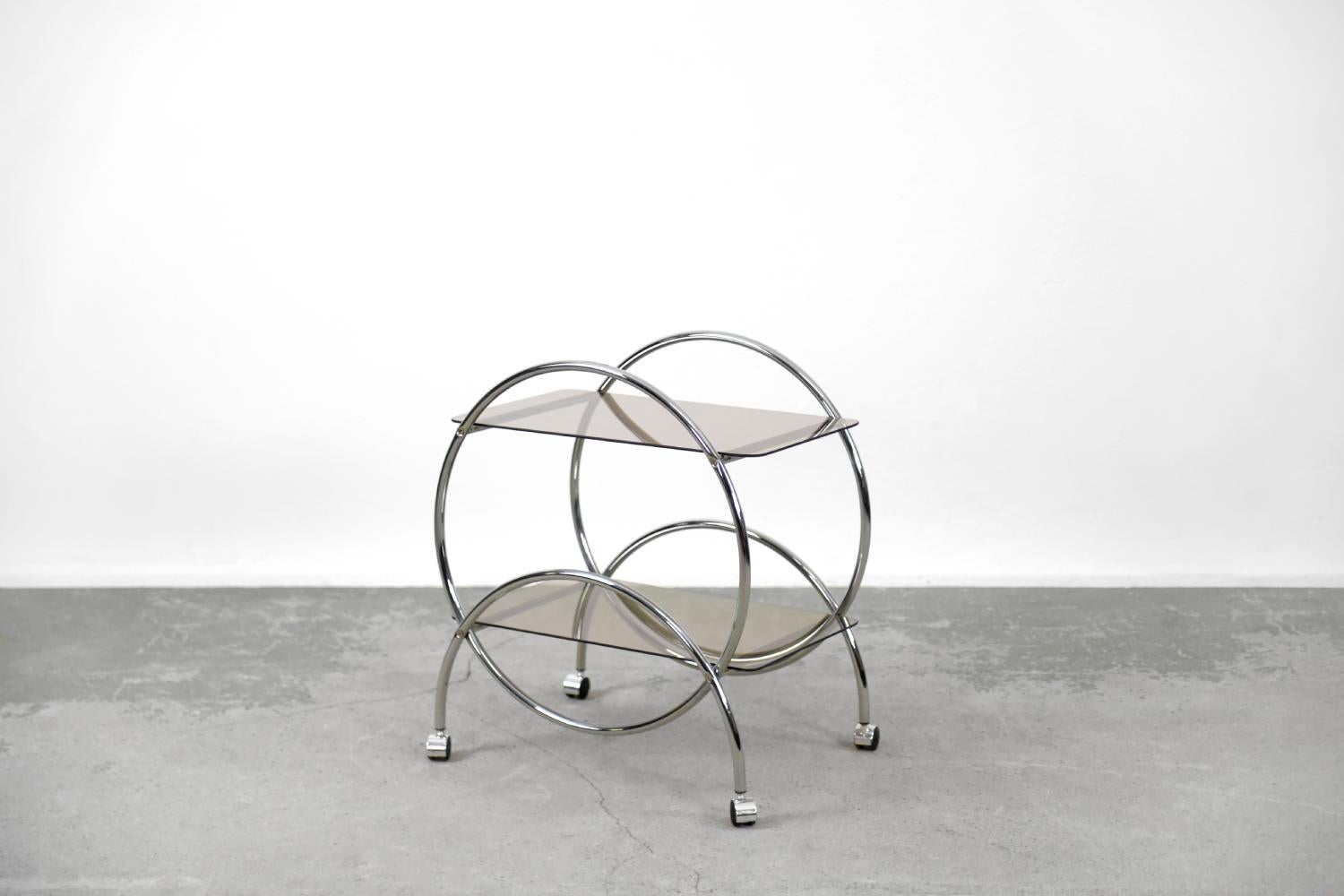 Dieser runde Stehtisch mit zwei Ebenen wurde in den 1970er Jahren von der schwedischen Firma IKEA hergestellt. Seine Form nimmt Bezug auf die Entwürfe der Bauhaus-Schule und des Art-dèco-Stils der Vorkriegszeit. Das geometrische Gestell ist aus