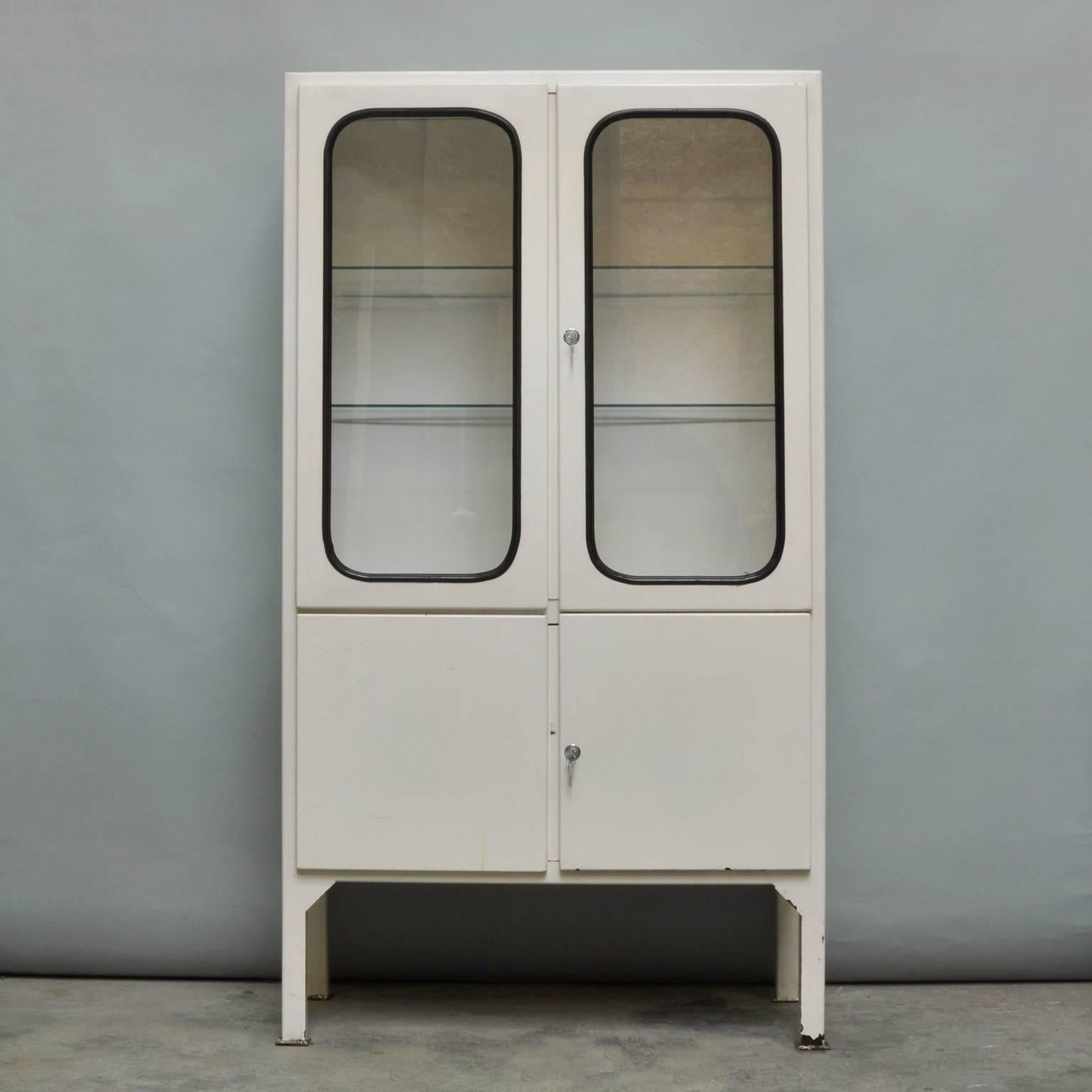 This medicine cabinet was designed in the 1970s and was produced, circa 1975 in Hungary. It is made from iron and antique glass, and the glass is held by a black rubber strip. The cabinet features two new adjustable glass shelves and functioning