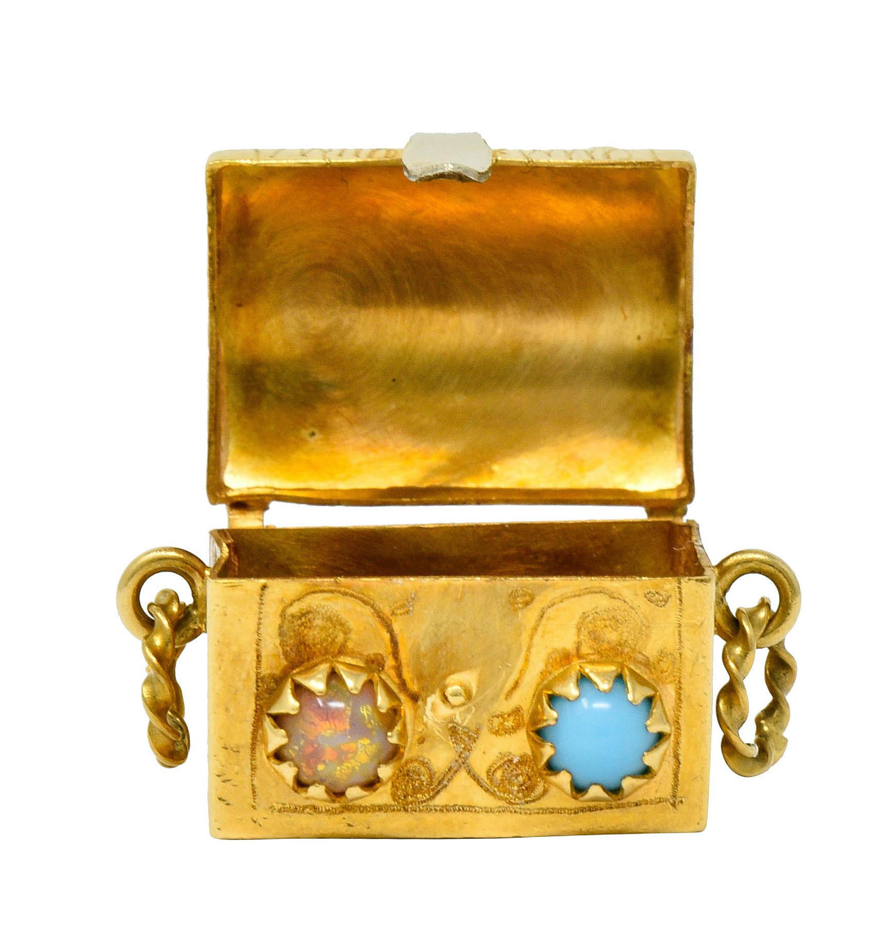 Treasure chest charm is designed as a rectangular form

That opens on a hinge to reveal a box-like cavity

Chest is accented by round glass cabochons; turquoise and opal inspired

With twisted rope articulated handles, a polished white gold clasp,
