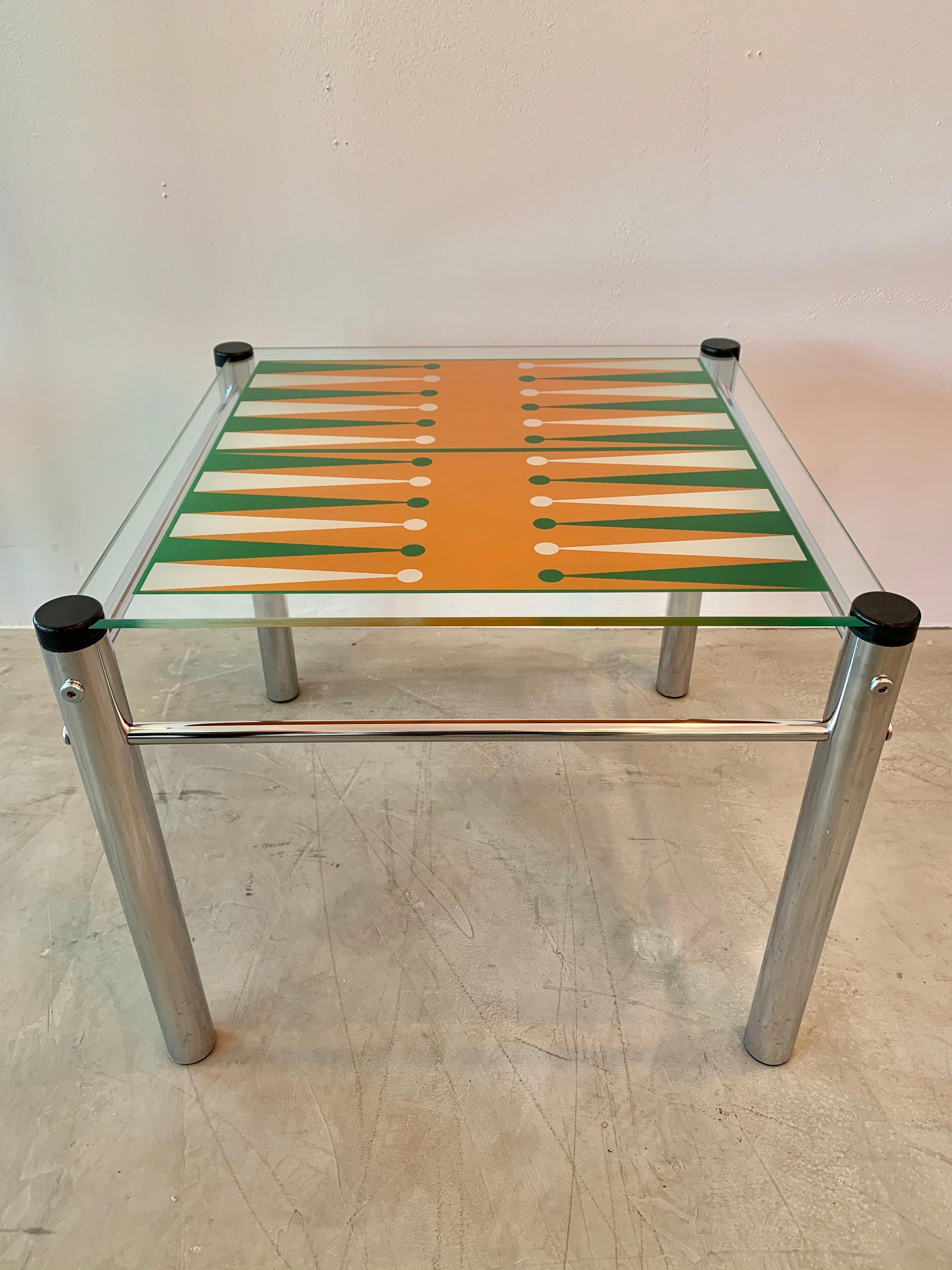 Colorful vintage glass and chrome backgammon table from the 1970s. Vibrant style with orange, green, and white glass top with metal legs. This is coffee table height. Can also be used as a side table between two chairs.