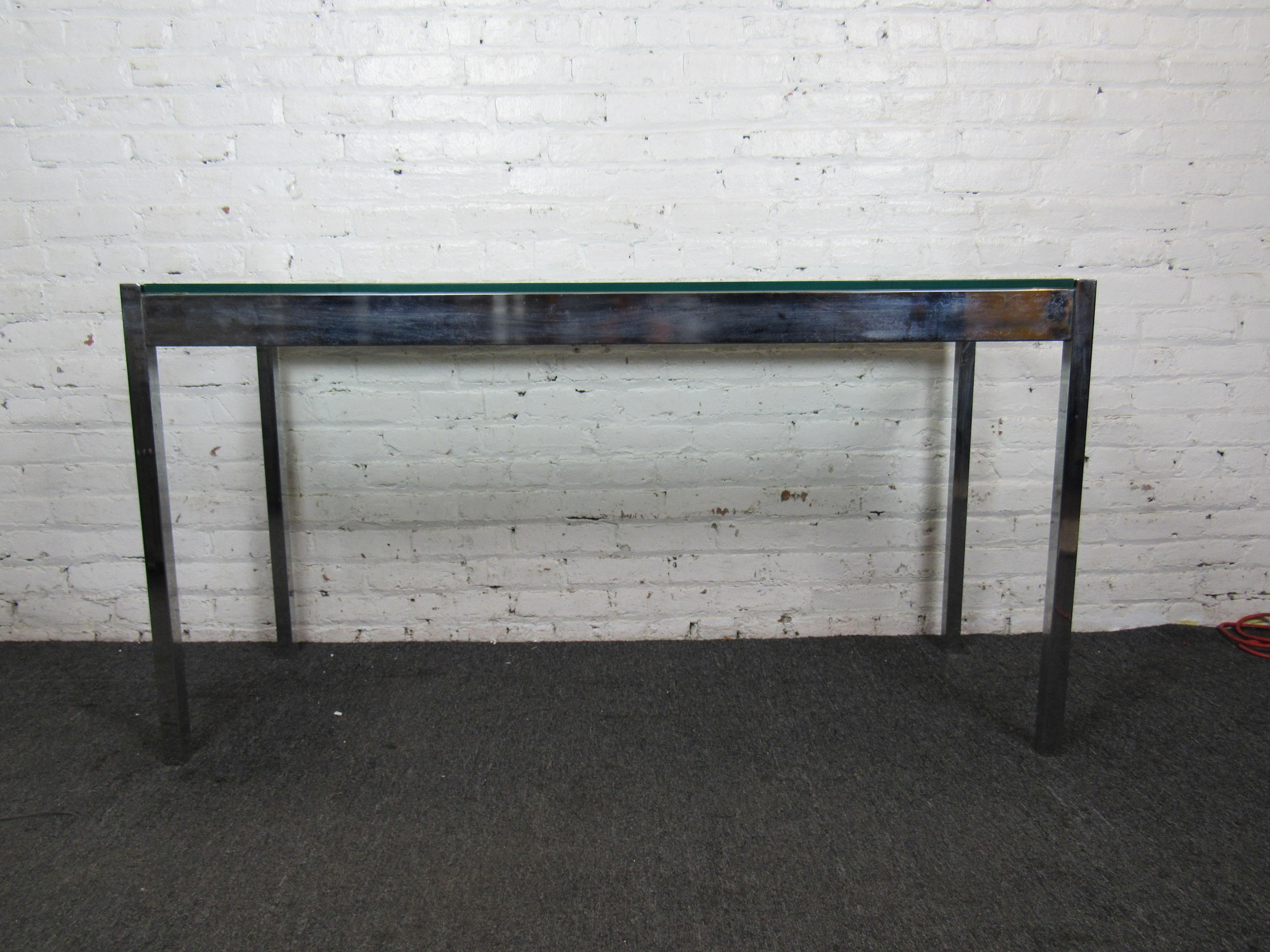 This vintage Mid-Century Modern console table features an elegant combination of a minimal chrome frame and a glass top. Please confirm item location with seller (NY/NJ).