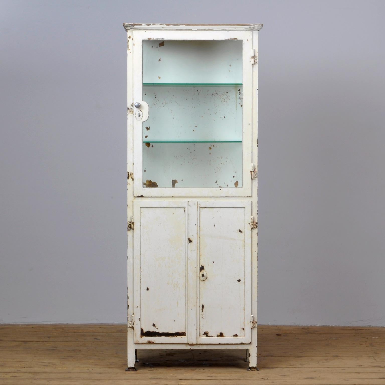 Medicine cabinet from the 1920s with a weathered appearance. Made from thick iron with an edge of wood on top. Lock of the upper door is missing but the door closes properly. Treated against rust.