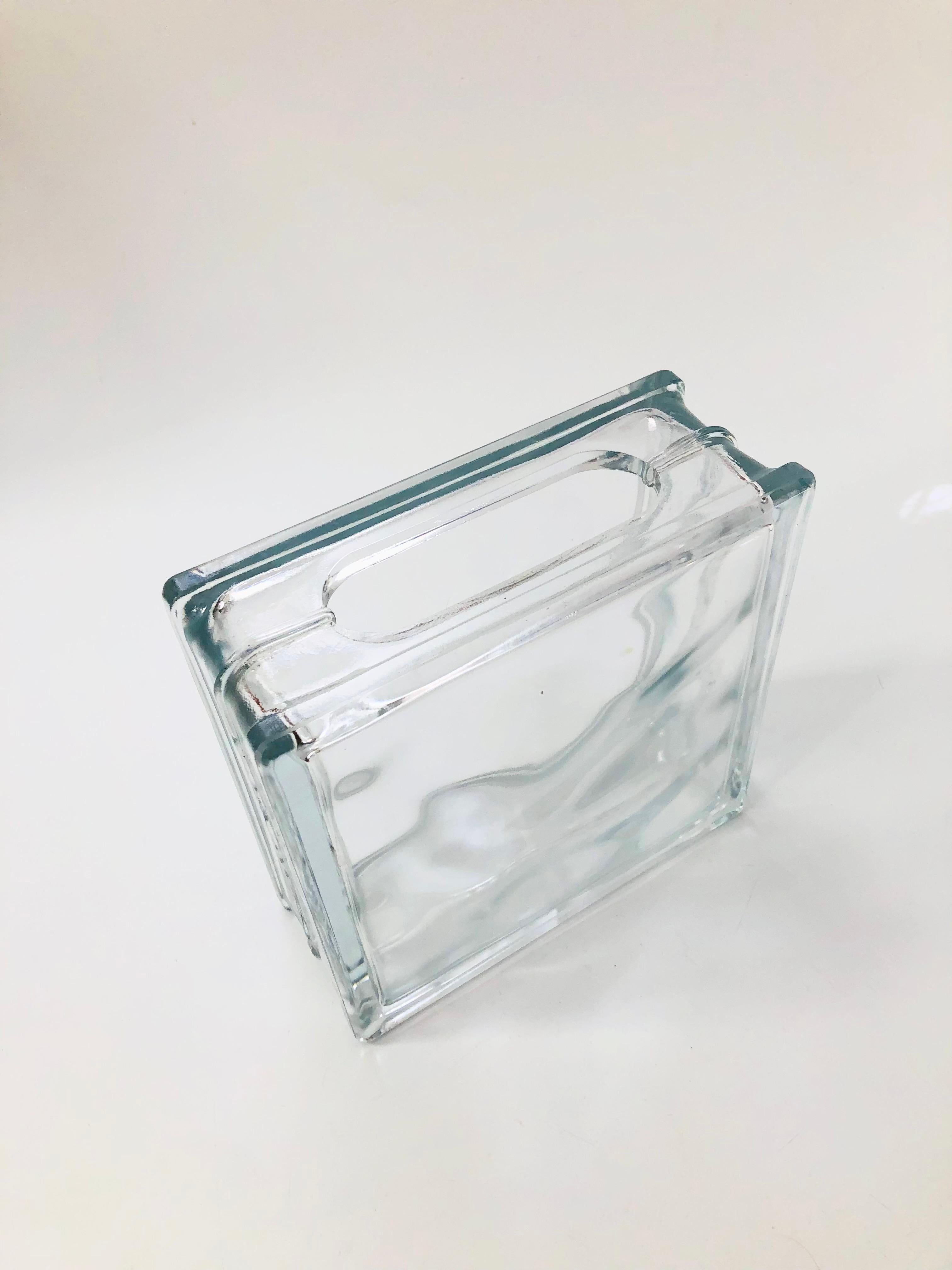 A unique vintage vase made from a glass block. A rounded rectangular opening has been cut into the top for use as a vase. Nice heavy weight, would work well doubling as a bookend.

