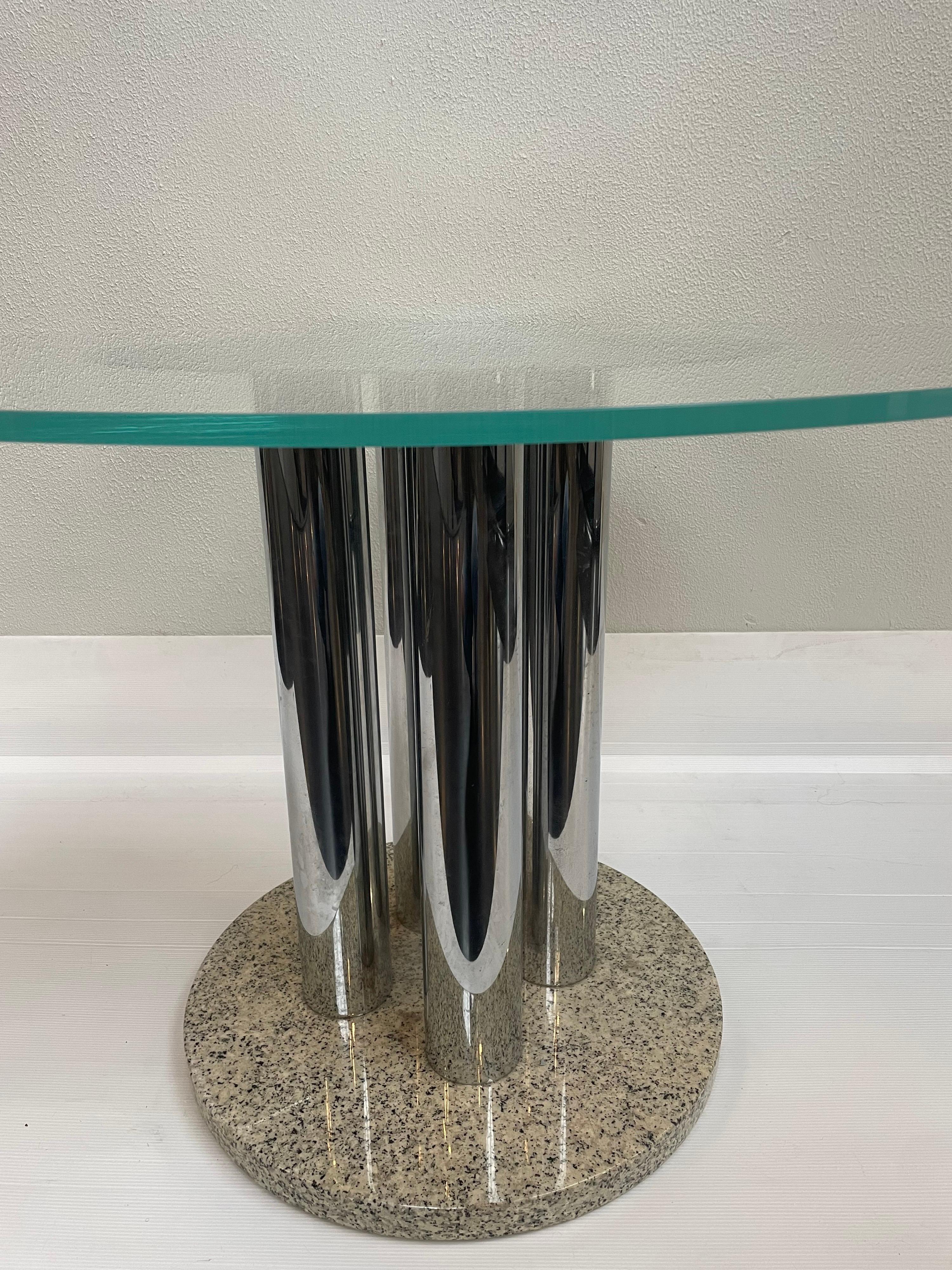 1970s Italian round dining table by Zanotta. A polished granite circular base with four chrome columns and a thick round glass top.