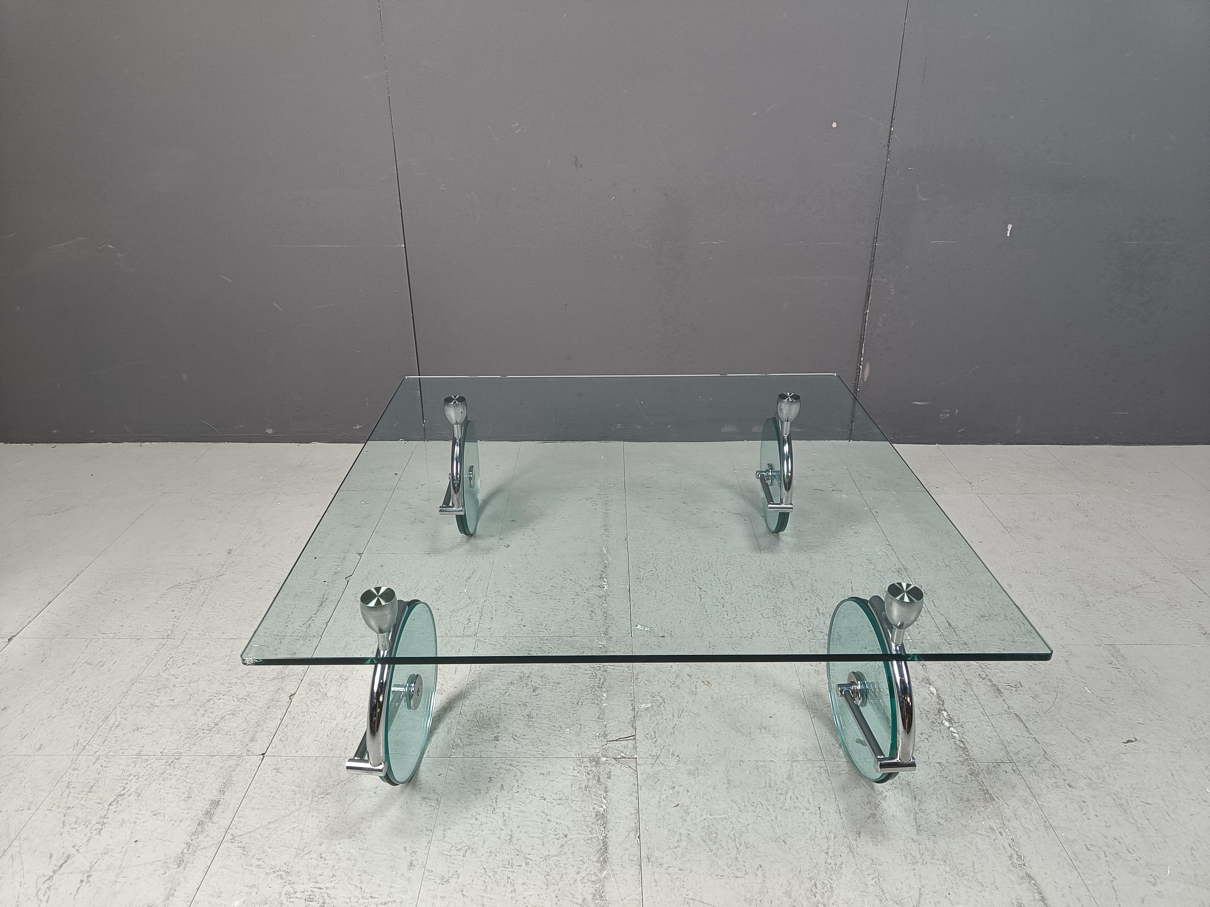 Tavolino senza tempo alla maniera di Gae Aulenti per Fontana arte. Spesso viene erroneamente venduto come un suo disegno.

Realizzato con un piano in vetro trasparente spesso, gambe scolpite in cromo per sostenere le ruote in vetro trasparente che