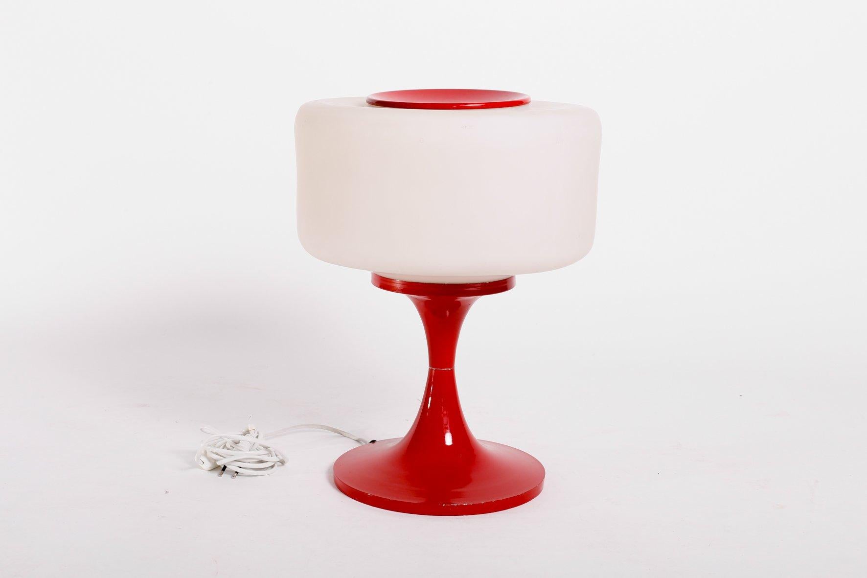 This space age style glass and enameled steel table lamp features an excellent 1960s style design.
It has a large glass shade and a painted enameled steel frame. This vintage item remains fully functional, but it shows sign of age through some