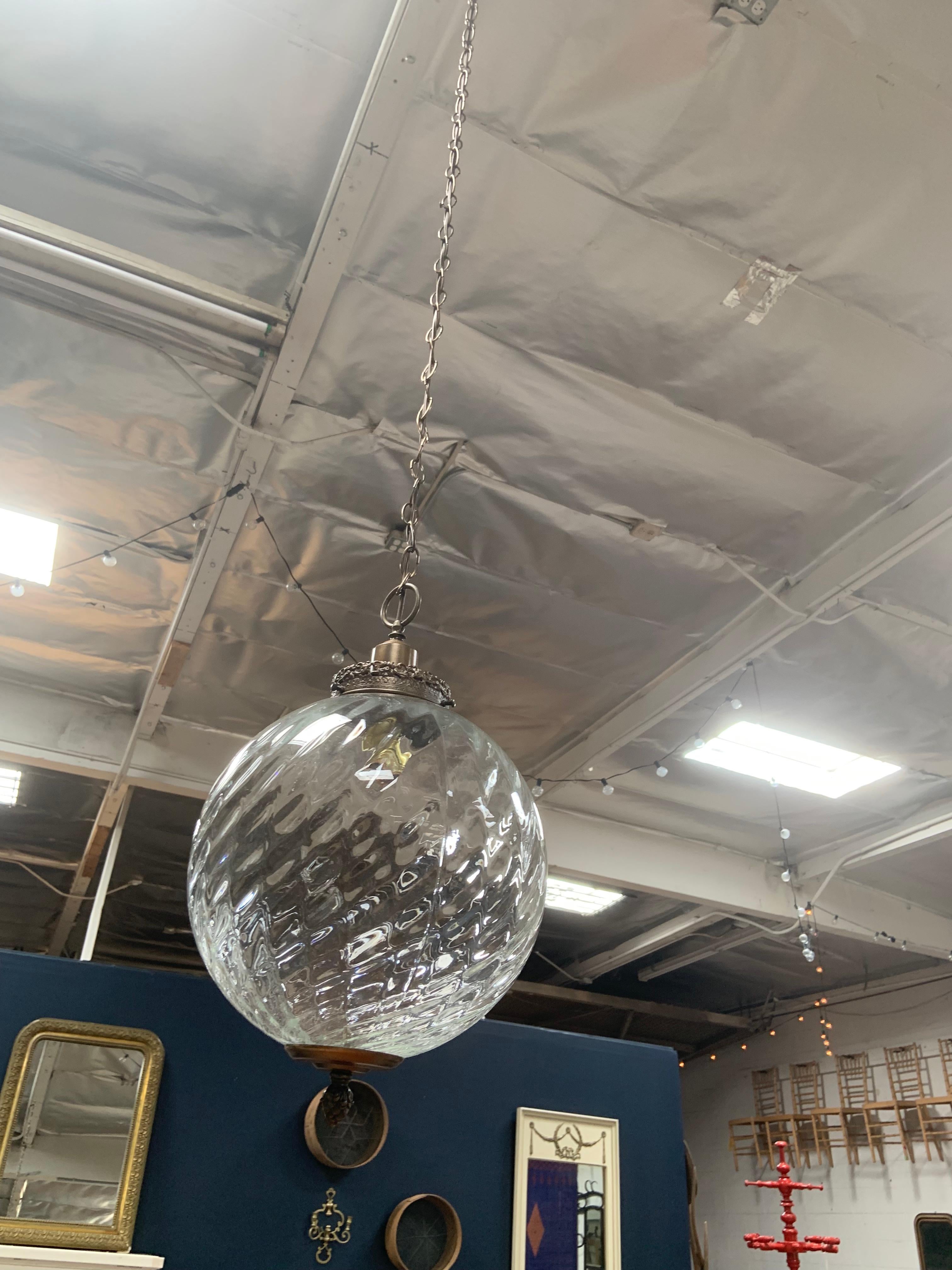 This uniquely designed glass hanging pendant has diagonal ridges and a brass base with Victorian style accents. The neutral, clear glass globe makes this piece fit beautifully in any space.