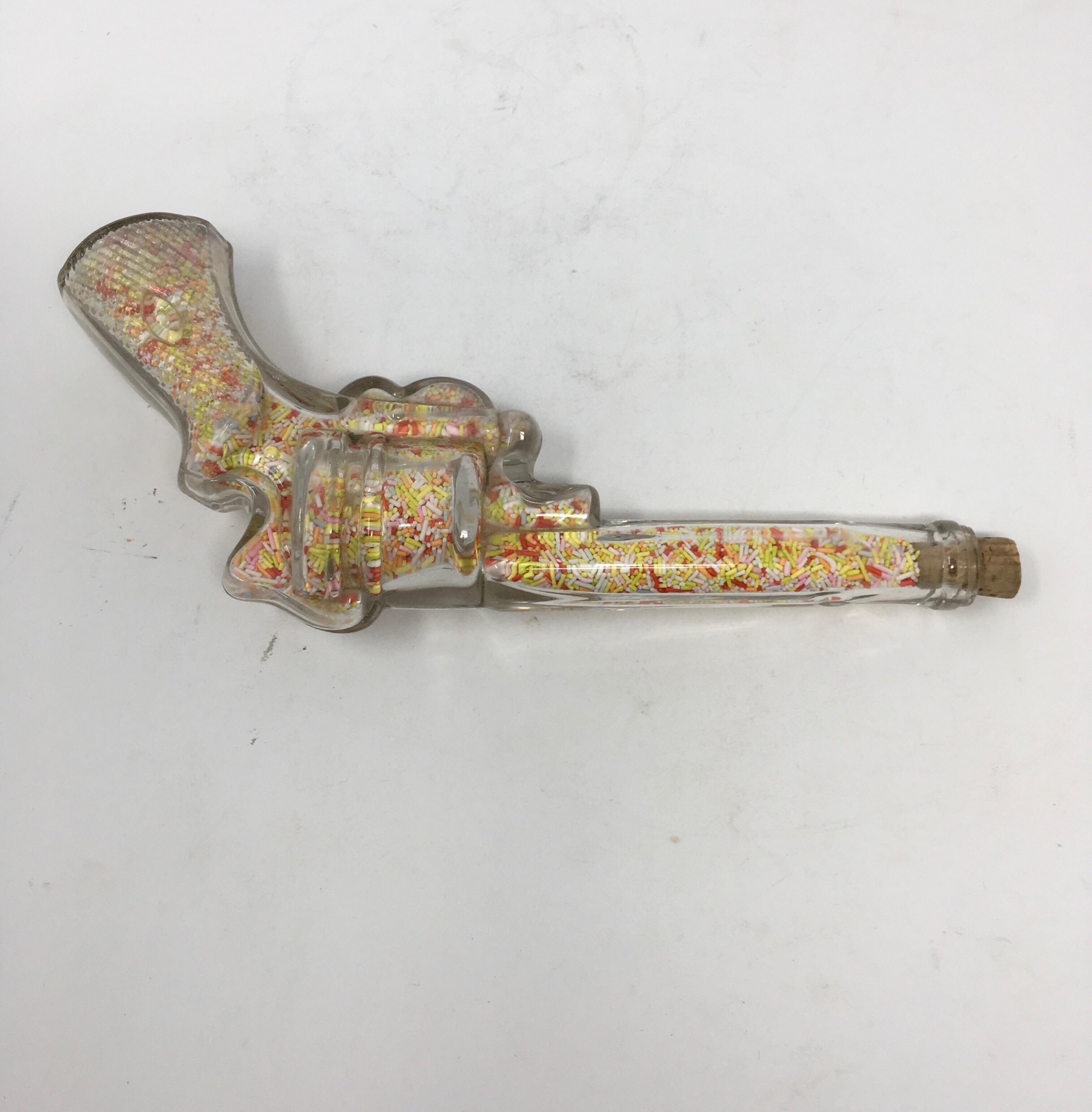 We found this vintage glass candy dispenser in the shape of a pistol in England. Glass candy containers from five and dime stores were very popular in the 1940s and 1950s. This candy container is complete with candy and a cork top. Cork was used to