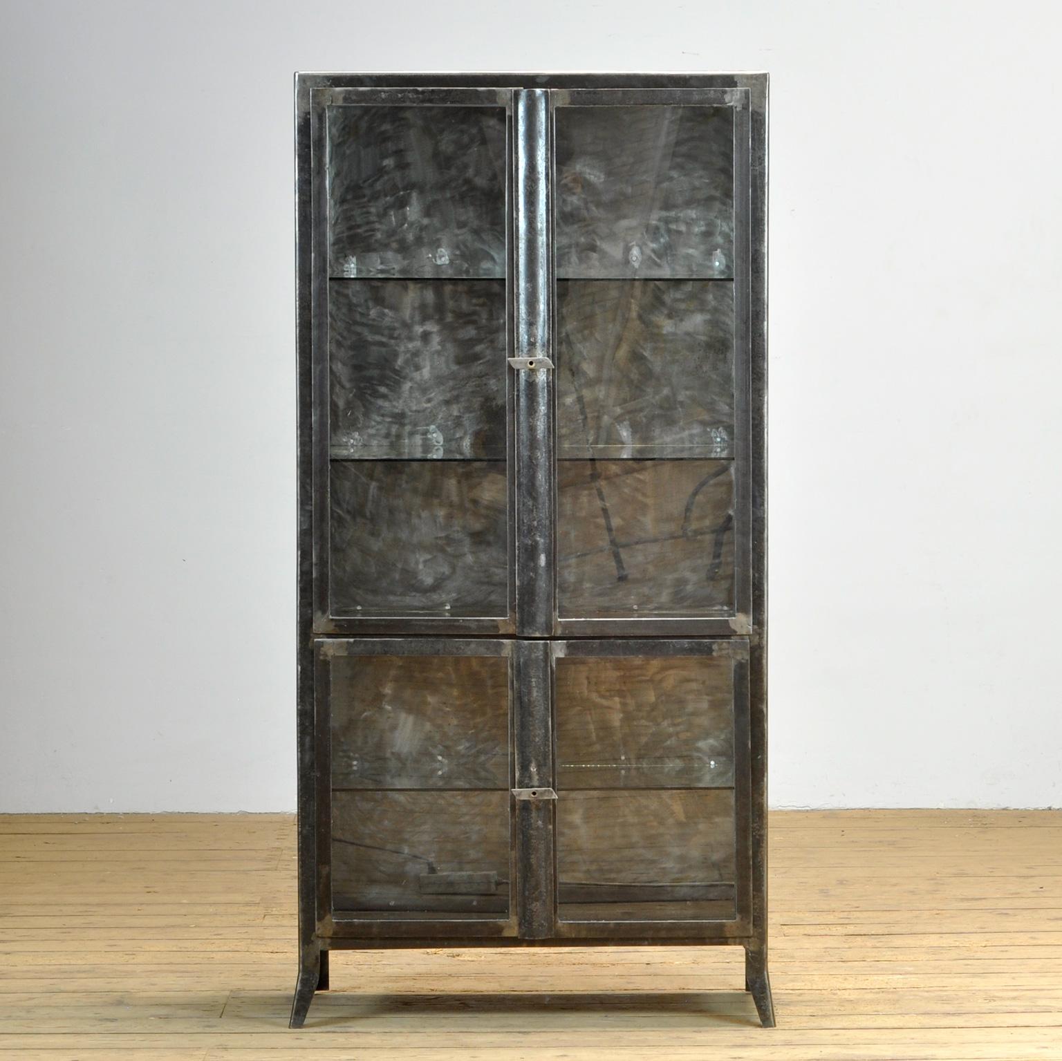 Medicine cabinet made of iron and glass. The cabinet is from the 1950s and was produced in Hungary. The cabinet is stripped down to the metal and finished with a transparent lacquer. The cabinet comes with 3 glass shelves. The shelves in the upper