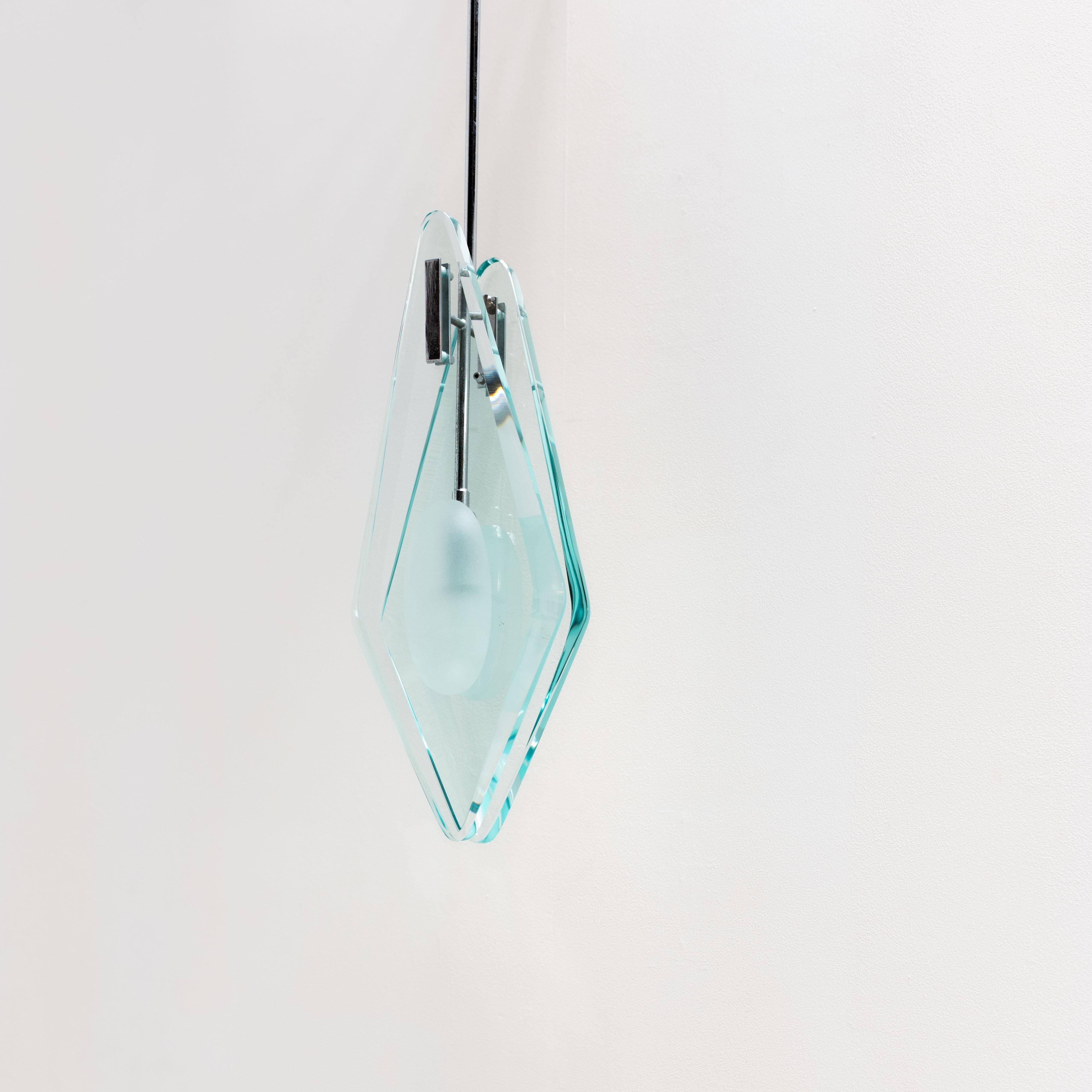 Un'elegante lampada a sospensione scultorea prodotta da Veca. Questo pezzo raffinato è caratterizzato da due spesse lastre di vetro a forma di diamante, tenute in tensione da una ferramenta cromata lucida, con un diffusore in vetro smerigliato