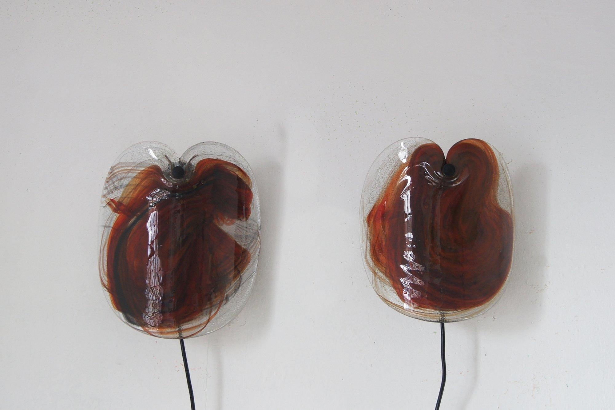 The unique Glassplattelampet wall lamp designed by Per Lütken for Holmegaard, Denmark, 1970s.
The bent glass pane is decorated inside with red orange with brown shades, which after ignition gives a very nice and warm glow.

The multi-colored