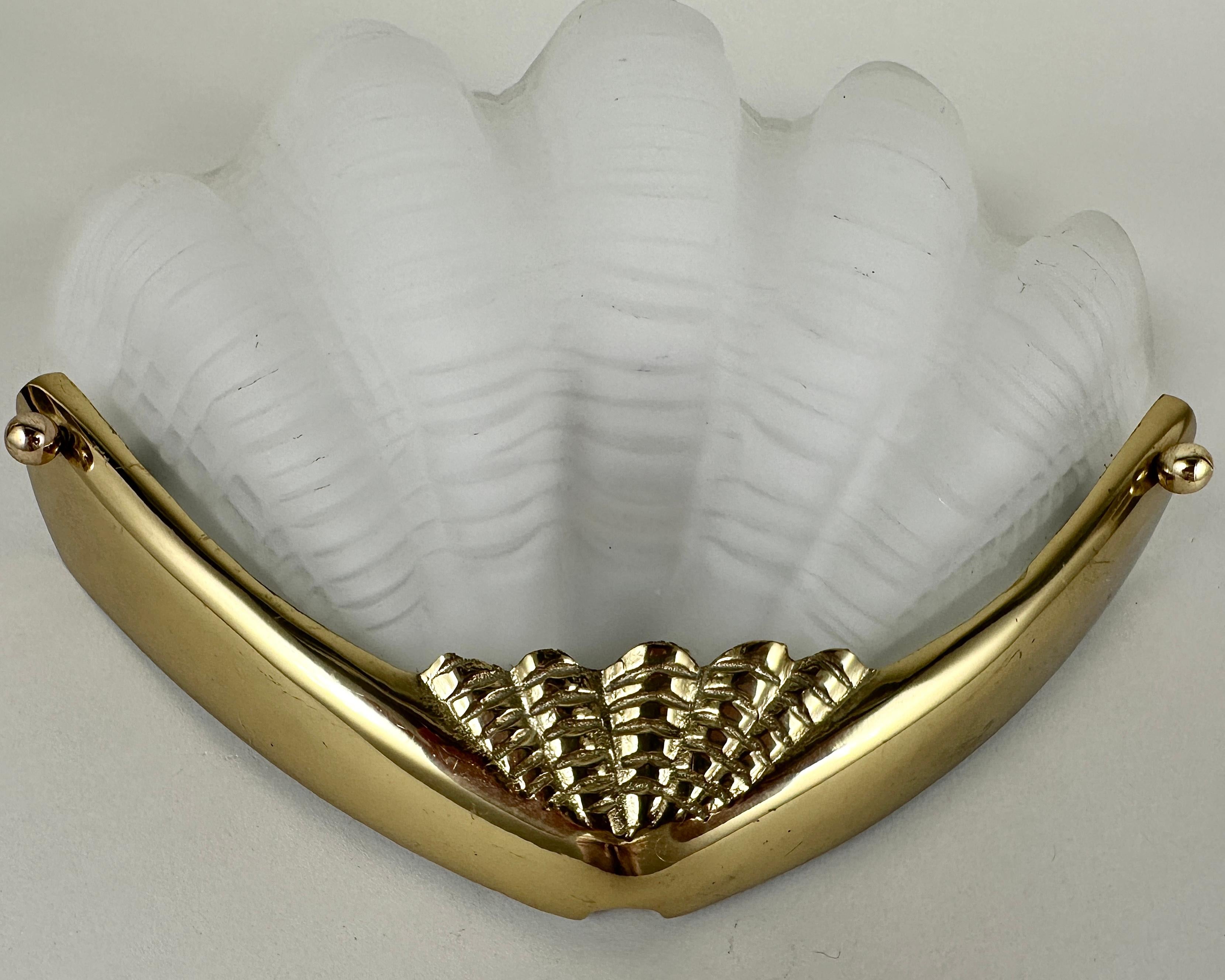 Amazingly beautiful glass wall lamp from the 80s.

The lamp has the shape of a shell.

The lamp is made of frosted glass with a bronze frame at the bottom.

The shell is very nicely designed.

With ridges in the glass and a nice corrugated edge at