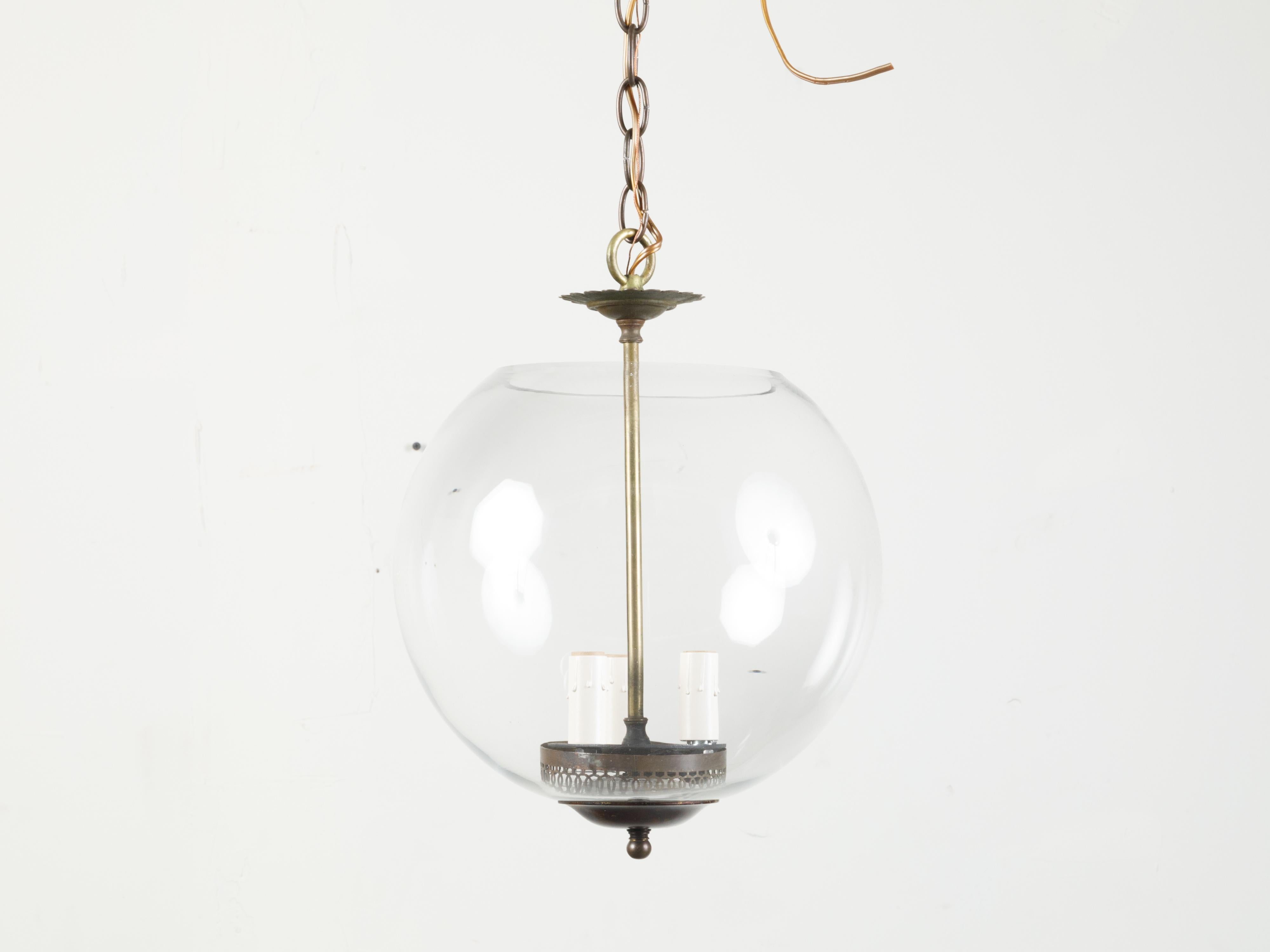 A vintage glass sphere light fixture from the mid 20th century, with three lights, rewired for the US. Created during the 20th century, this vintage glass light fixture features a spherical body securing three light bulbs connected to a central