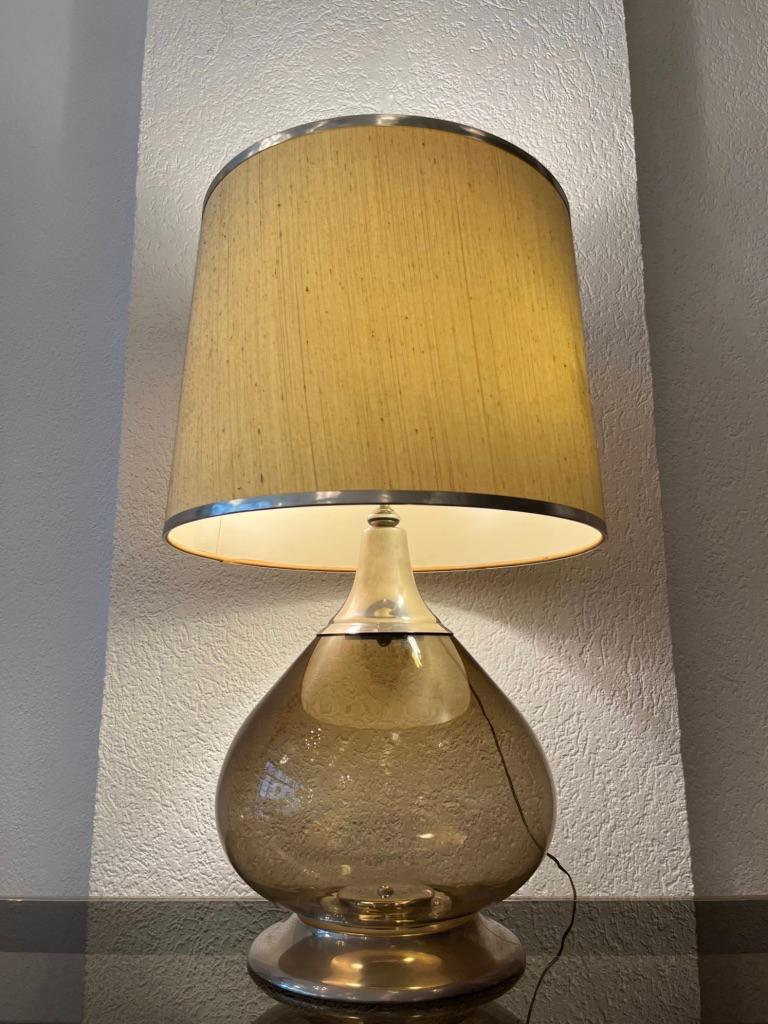 Tischlampe aus mundgeblasenem Rauchglas mit originalem Schirm mit silberner Verzierung.
3 Position der Beleuchtung. Nur oben (1 Glühbirne), nur unten (2 Glühbirnen) und alle zusammen (3 Glühbirnen)